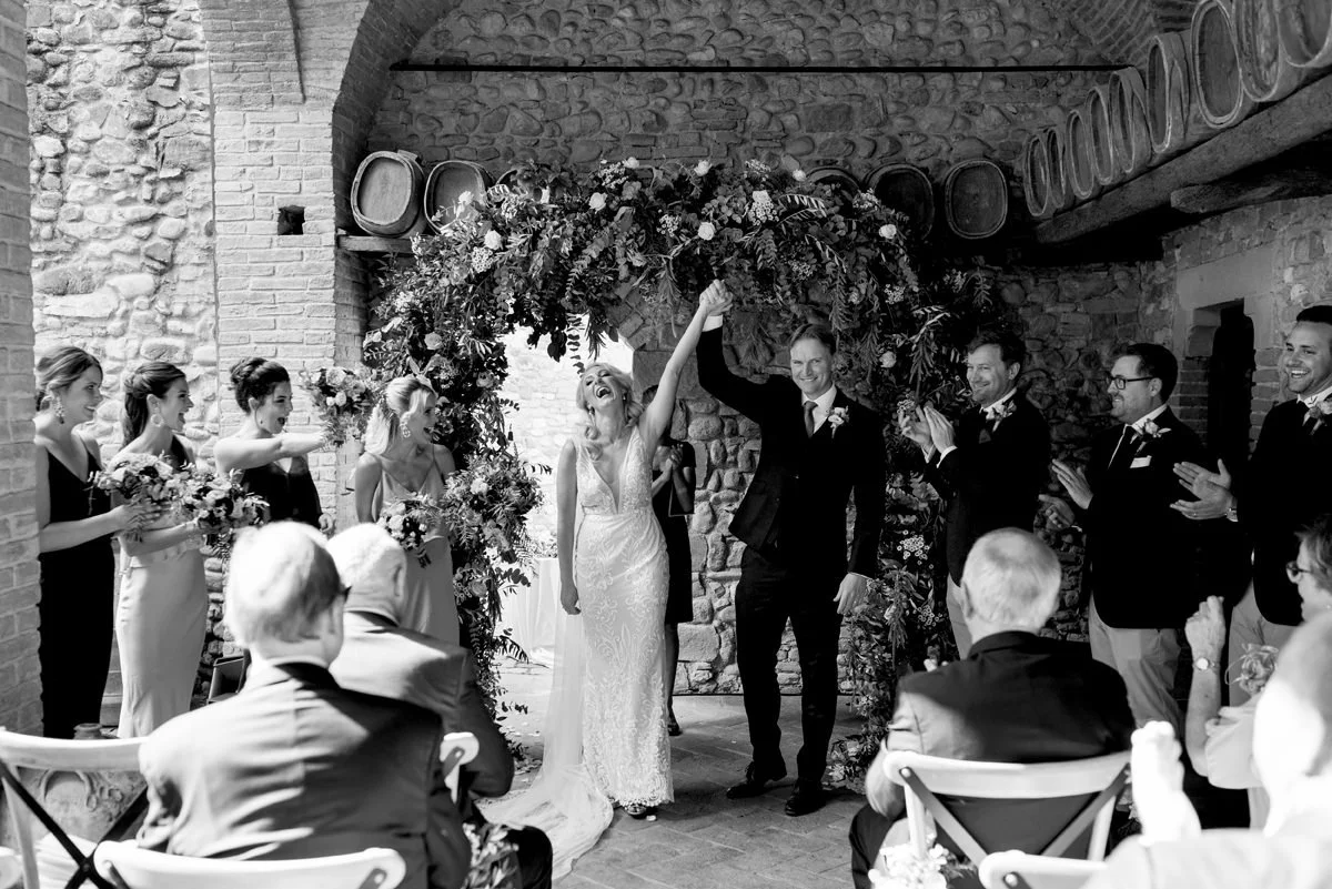 Bruidspaar viert hun huwelijk na de ceremonie bij Castello di Bibbione – een spontaan en vreugdevol moment vastgelegd door FunkyBird, trouwfotograaf in Toscane en Italië.