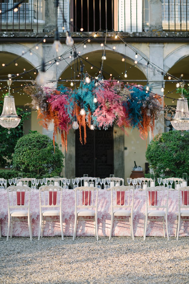 Adembenemende tafeldecoratie bij Borgo della Meliana, met lange Toscaanse cipressen op de achtergrond – elegante bruiloftsstyling in Italië met bloemen en sfeerdesign van FunkyBird.