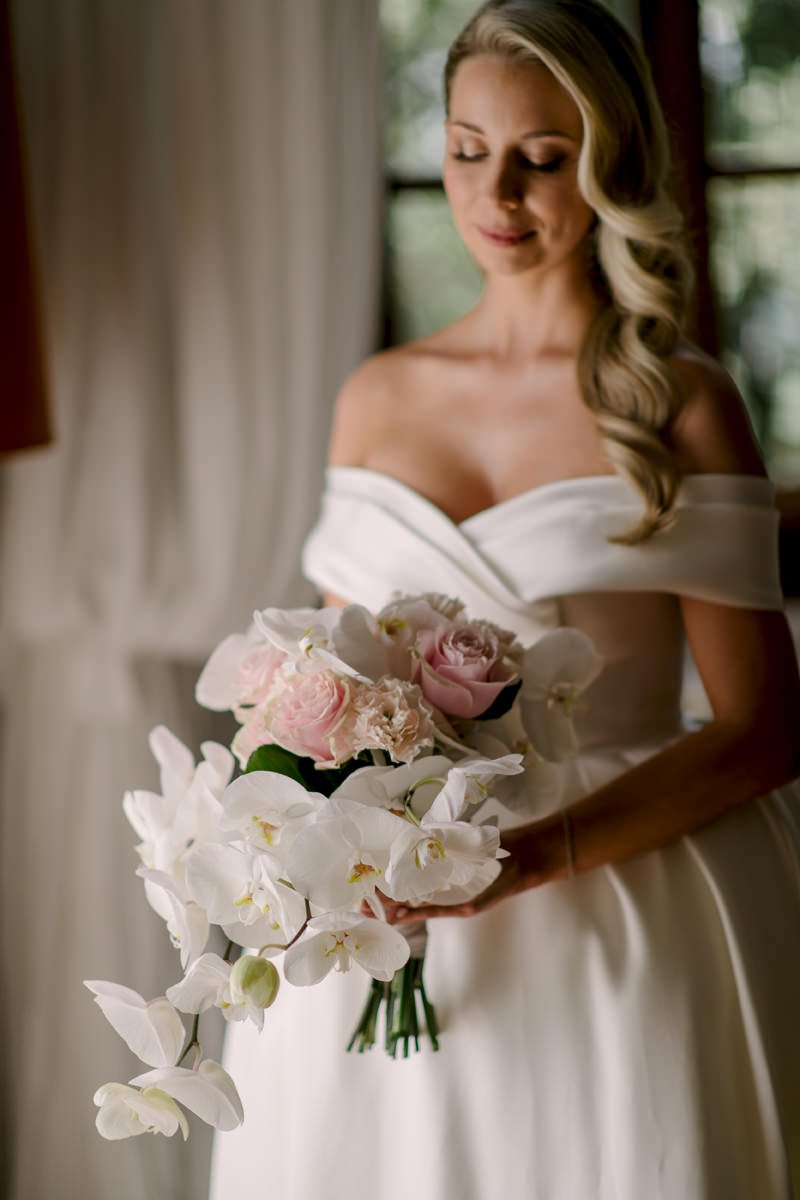 Bruid in een zijden, elegante trouwjurk met een opvallend orchideeënboeket bij Villa di Ulignano – een stijlvol moment vastgelegd door FunkyBird, trouwfotograaf in Toscane en Italië.