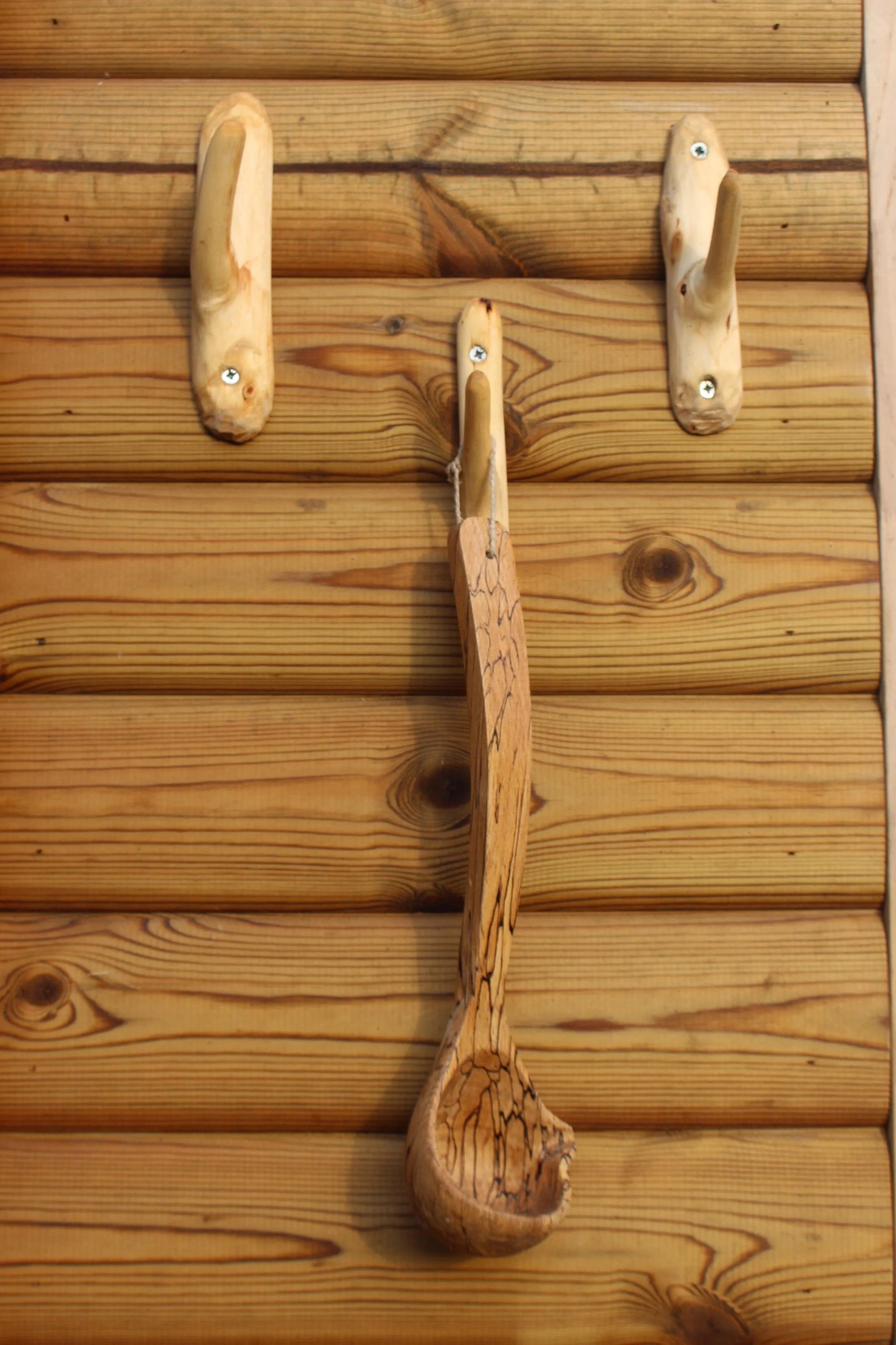 Wooden wall hooks with a fish-shaped hook in the center, all mounted on a wooden wall.