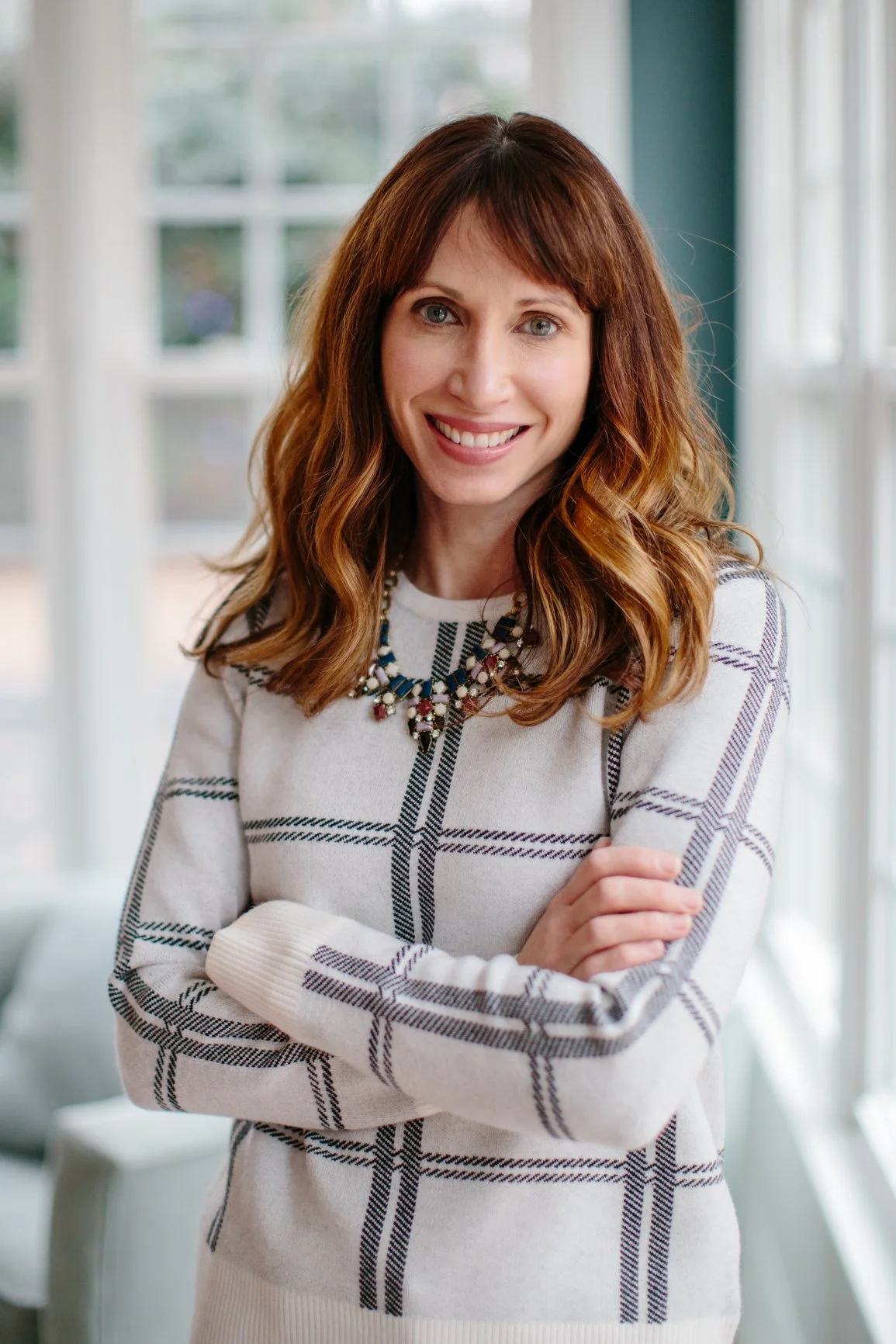 A beautiful red haired woman with warm blonde highlights and wavy hair with a gorgeous smile