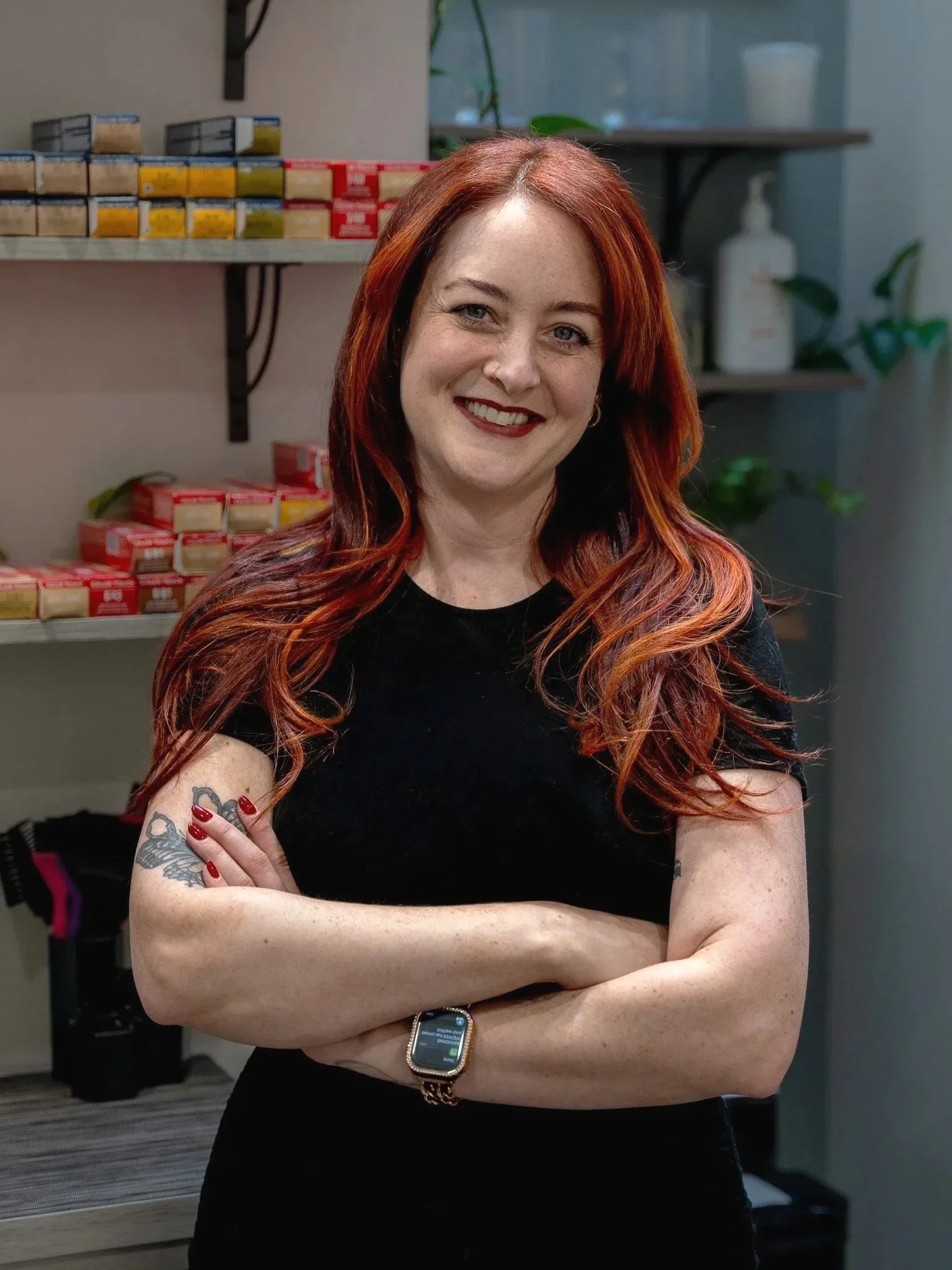 Laura Chavich, owner of Laura Jayne Hairstylist, standing in her salon with her color bar behind her.