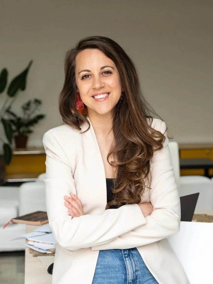 A woman with long, sleek brown hair that has been curled at the bottom smiling and looking happy.