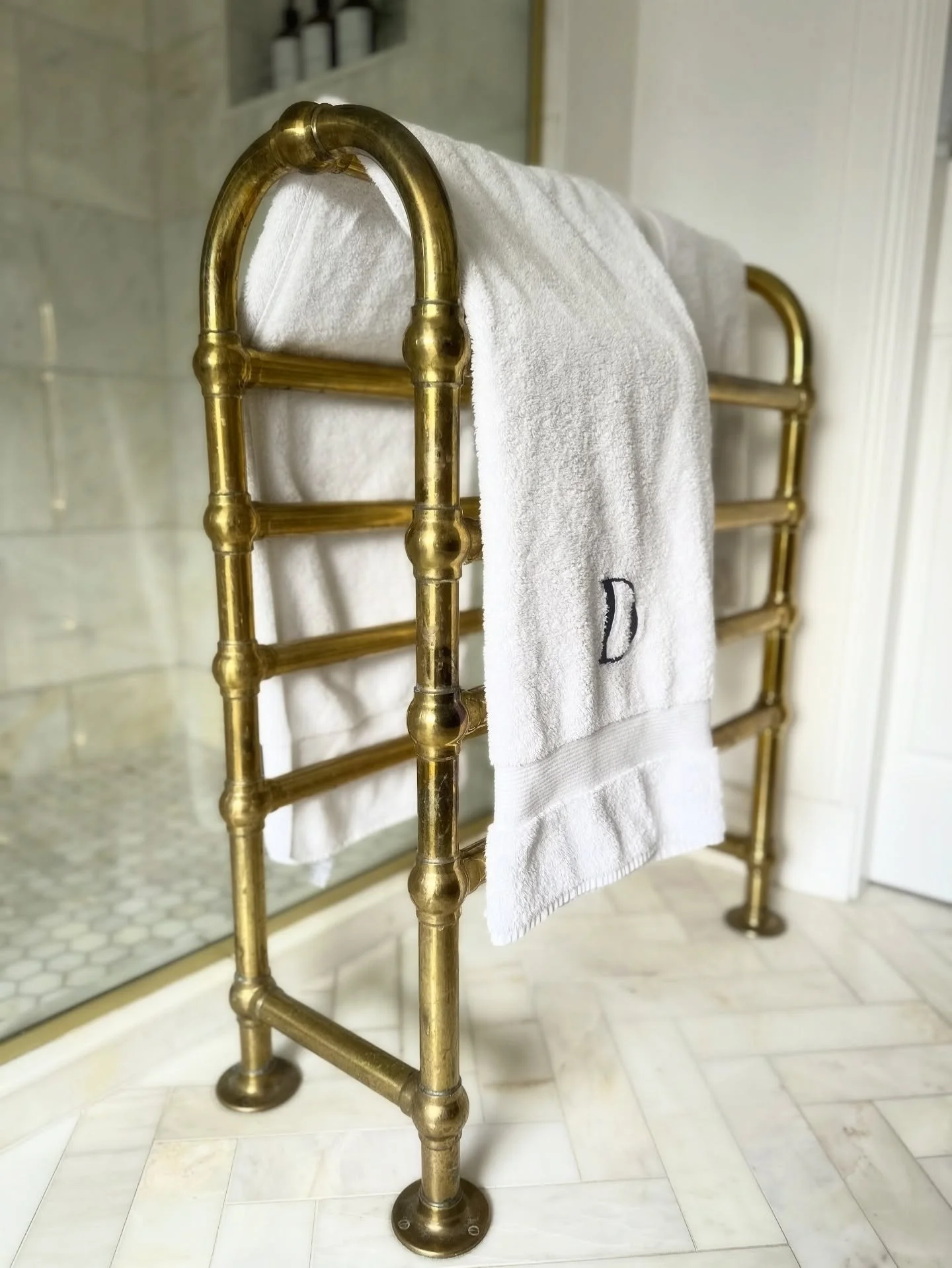 Details | Bathrooms 

A detail that quietly elevates the everyday &mdash; this antique brass heated towel rail brings warmth, texture, and a touch of heritage charm to a serene marble setting.

When wall space is limited, a freestanding design become