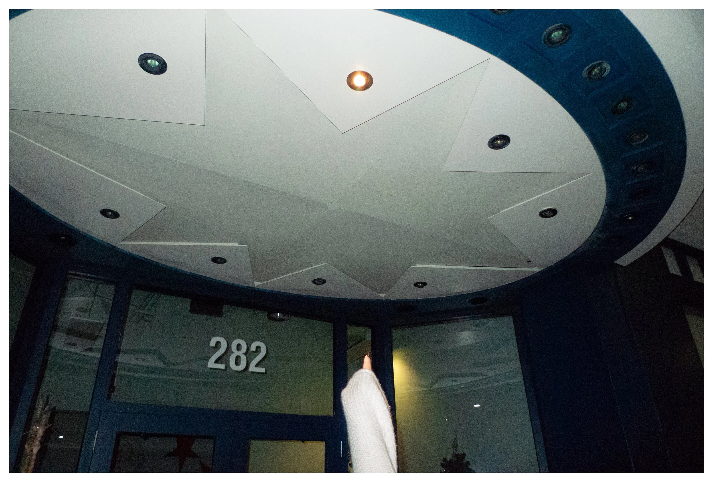 Ceiling with star shape design and multiple small recessed lights, above a dark blue door with the number 282.