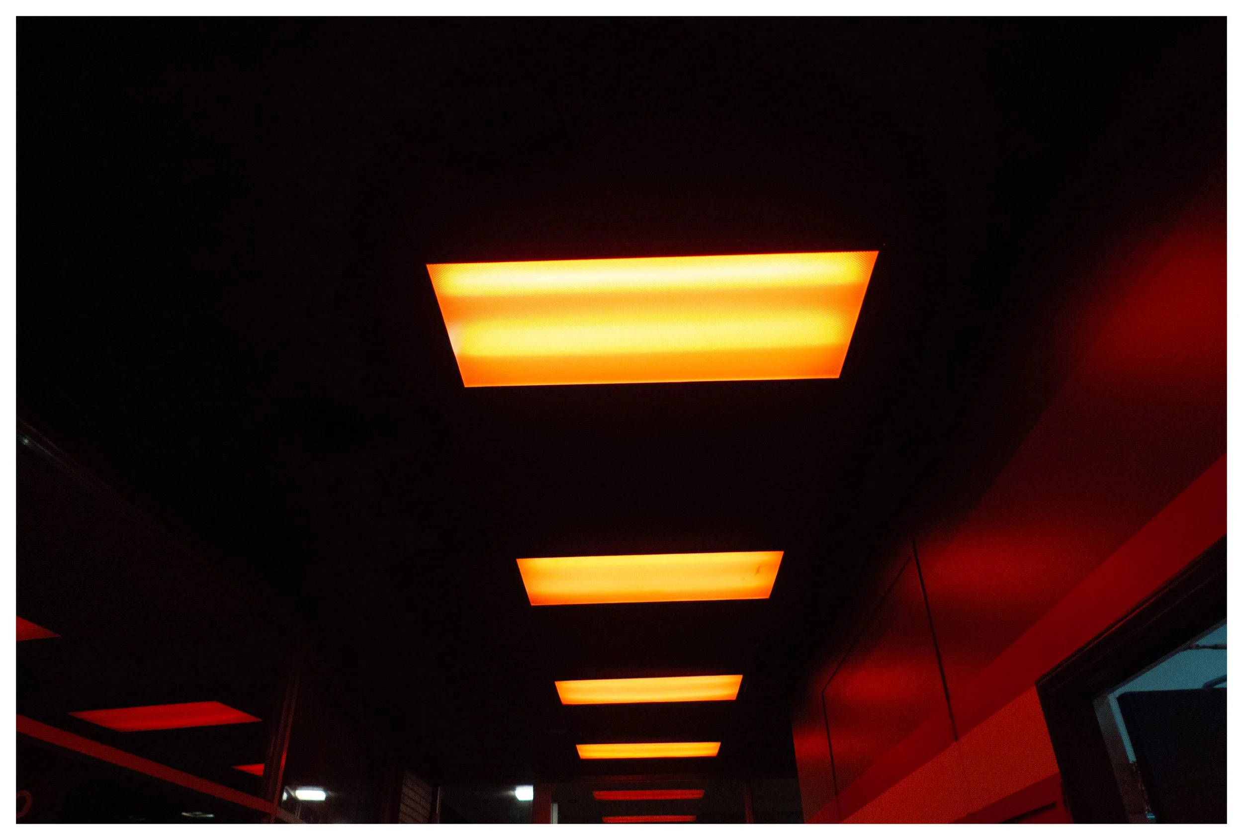 Dark ceiling with rectangular orange illuminated light fixtures in a row.