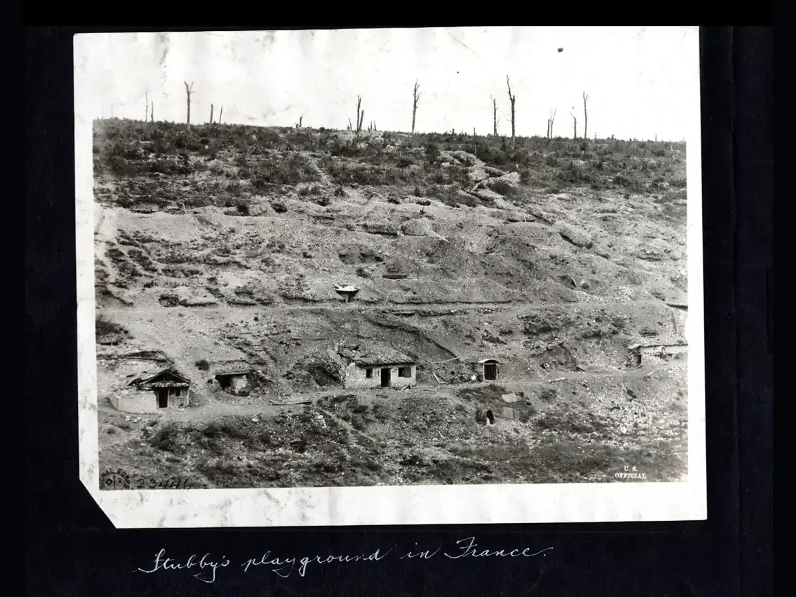 Black-and-white wartime landscape showing dugouts cut into a barren hillside in France during WWI