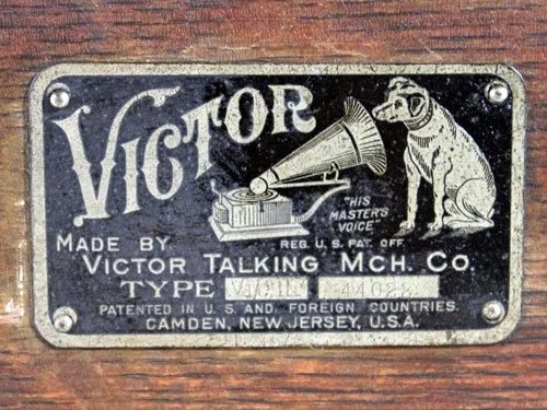 Close-up of a vintage Victor Talking Machine Company label featuring the iconic His Master’s Voice image of Nipper listening to a gramophone, mounted on a wooden surface.