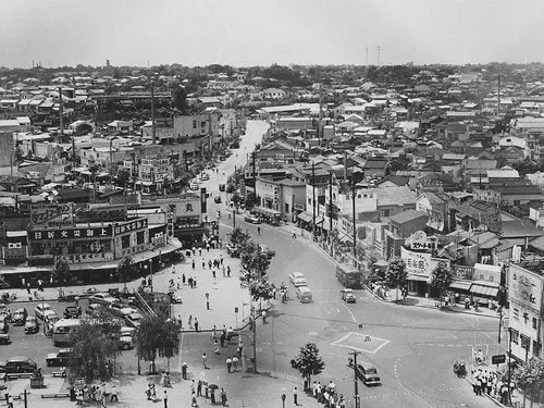 Aerial view of Shibuya in mid-20th-century Tokyo showing busy streets, buildings, and pedestrians.