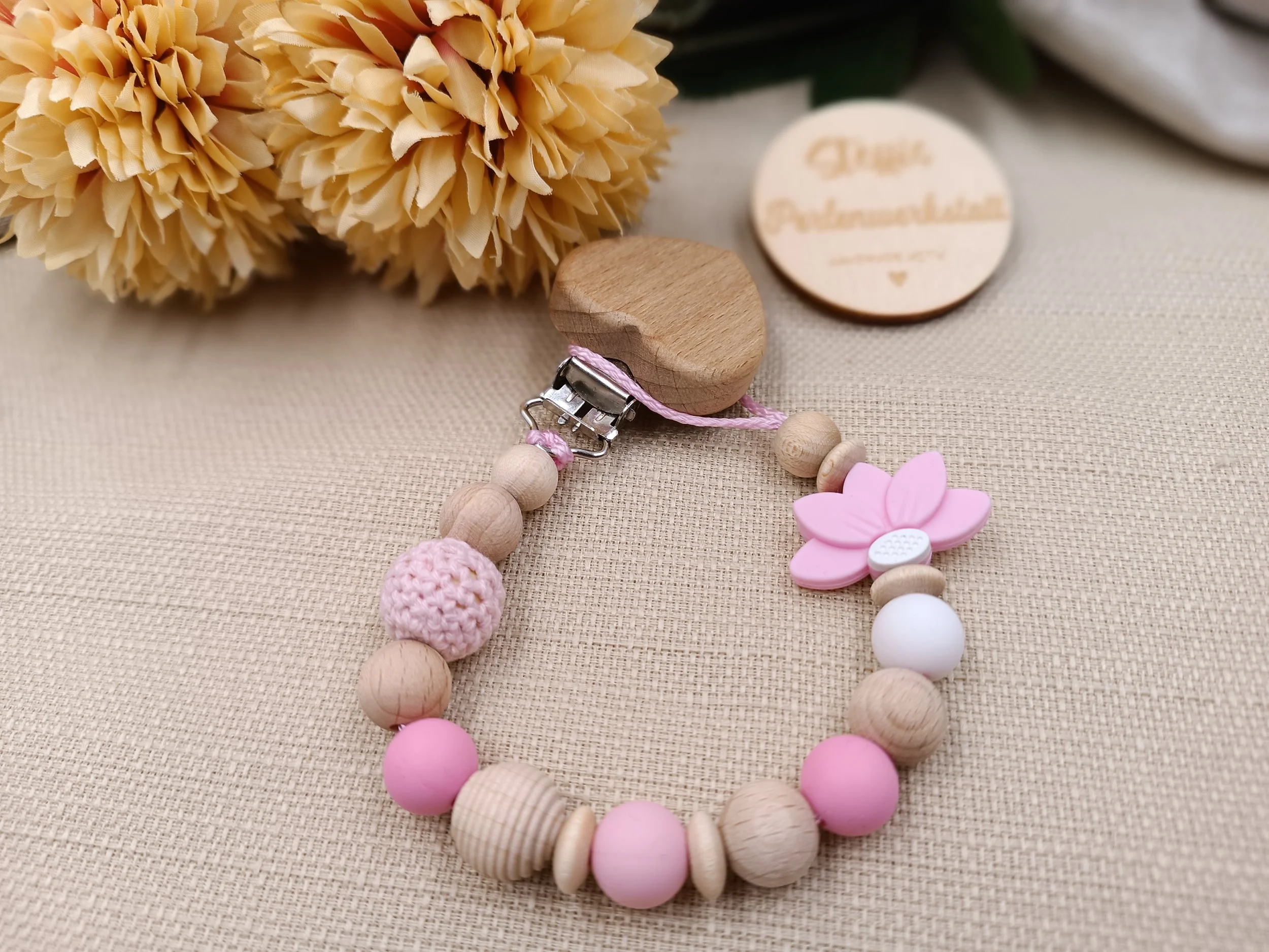 Schnullerkette
bestehend aus Holz,- Silikon- und Häkelperlen. Motivperle: halbe Blume, rosa
Preis 18 Euro 