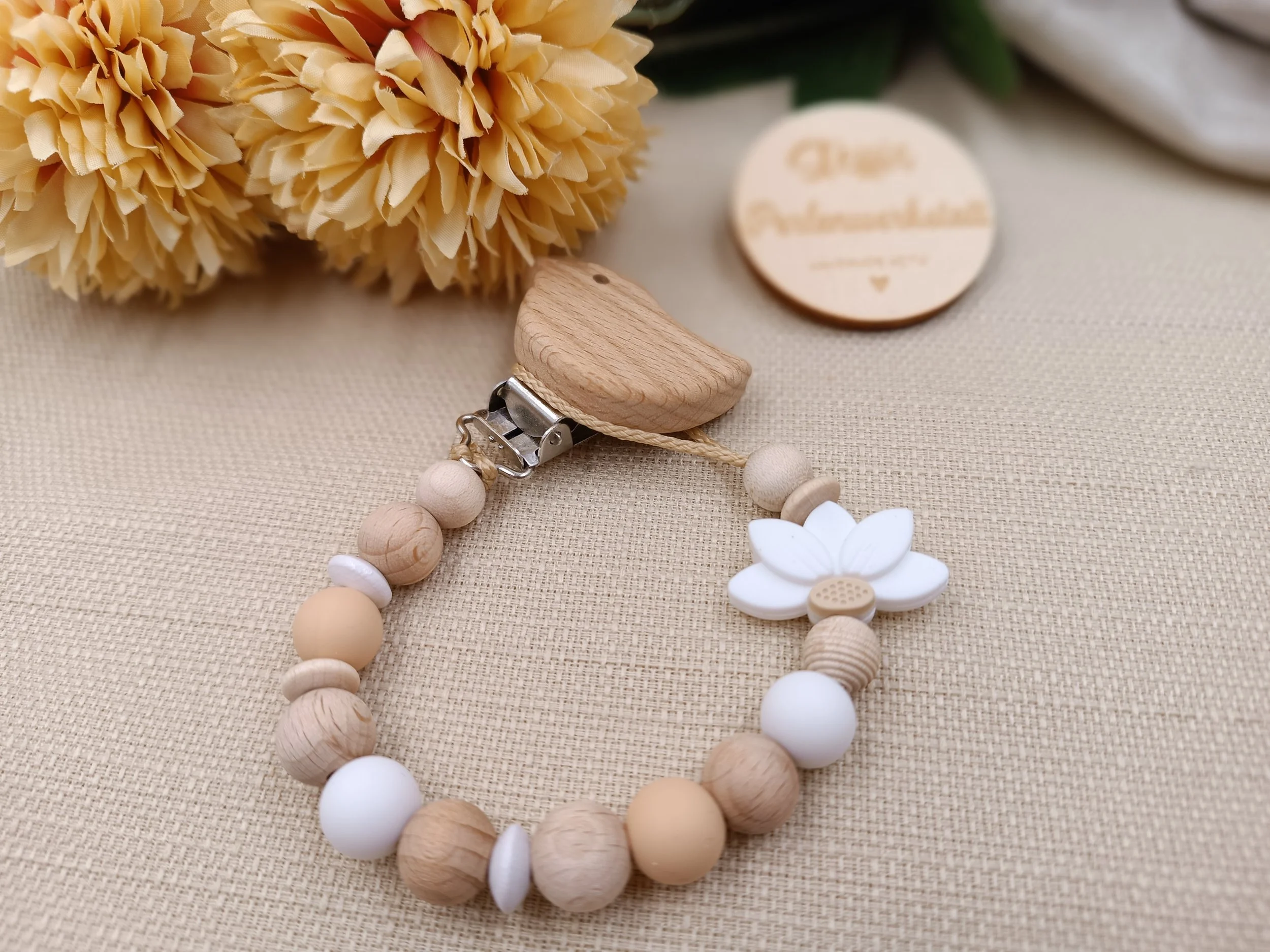 Schnullerkette
bestehend aus Holz- und Silikonperlen. Motivperle: halbe Blume, weiß
Preis 18 Euro 