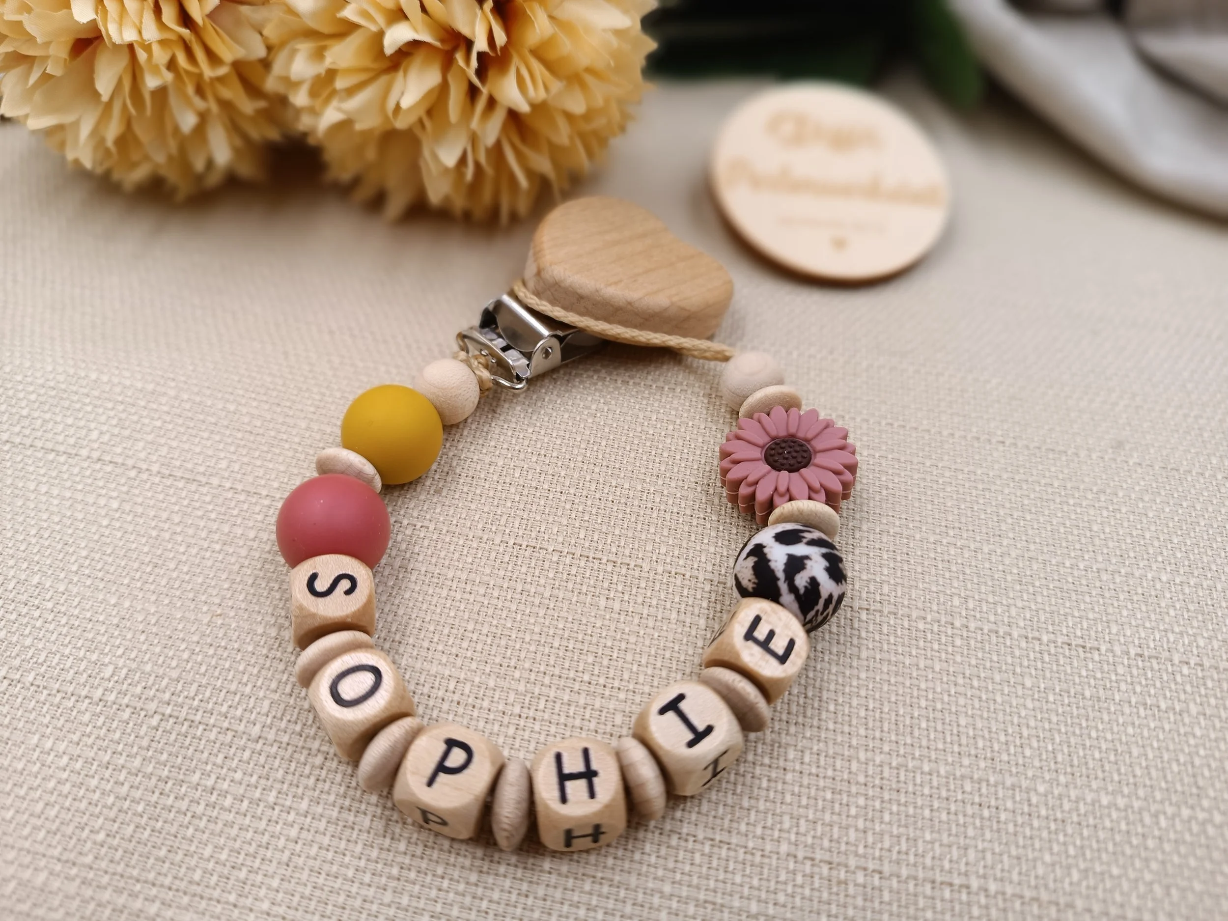 Schnullerkette personalisiert mit Holzbuchstaben,
bestehend aus Holz,- und Silikonperlen 
Preis 18 Euro je nach Länge des Namens