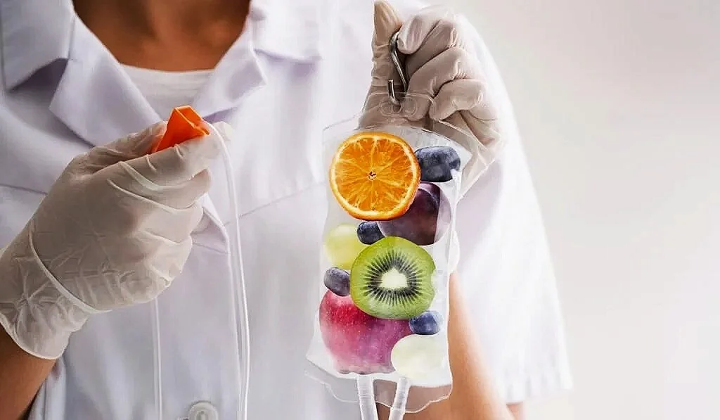 Person in medical gloves holding a bag filled with slices of orange, blueberry, kiwi, watermelon, and other fruits.