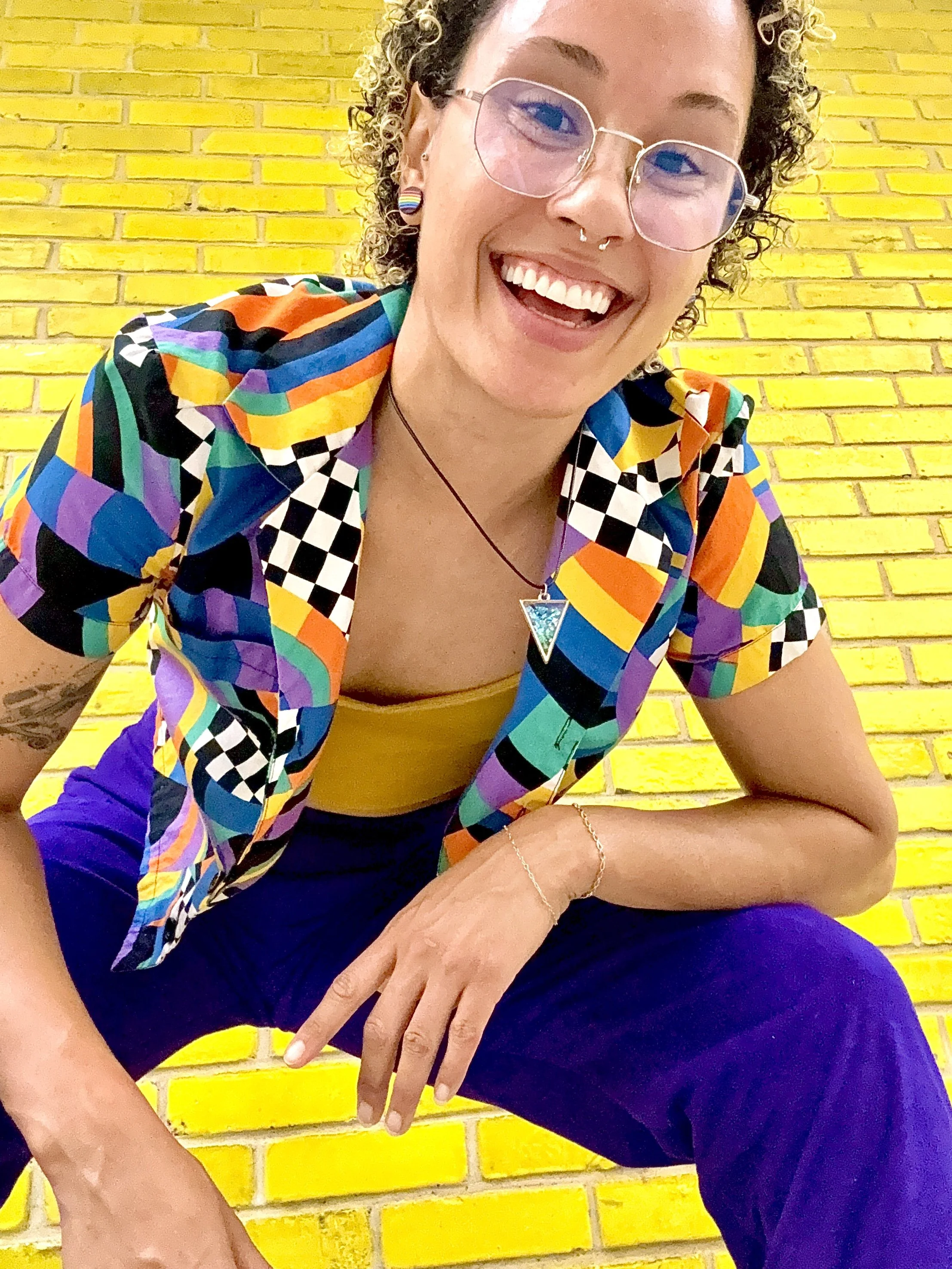 A smiling person in a brightly colored patterned shirt leaning down into the camera