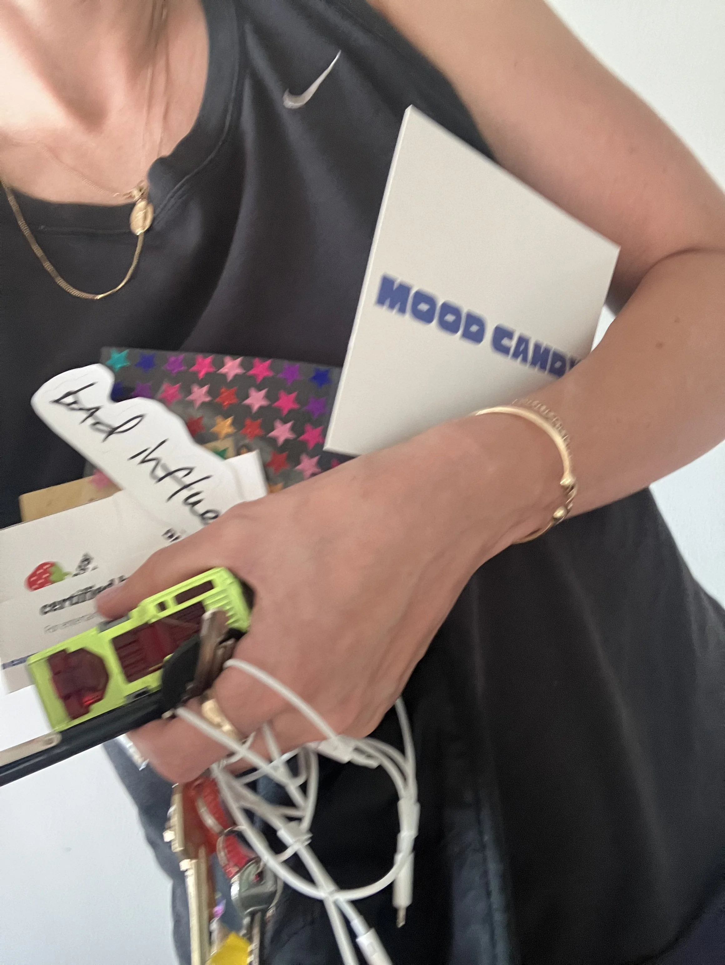 A person holding a variety of gift cards with a colorful star pattern and a white box with blue text reading 'ON BOARD'. The person is wearing a black Nike shirt and gold jewelry.