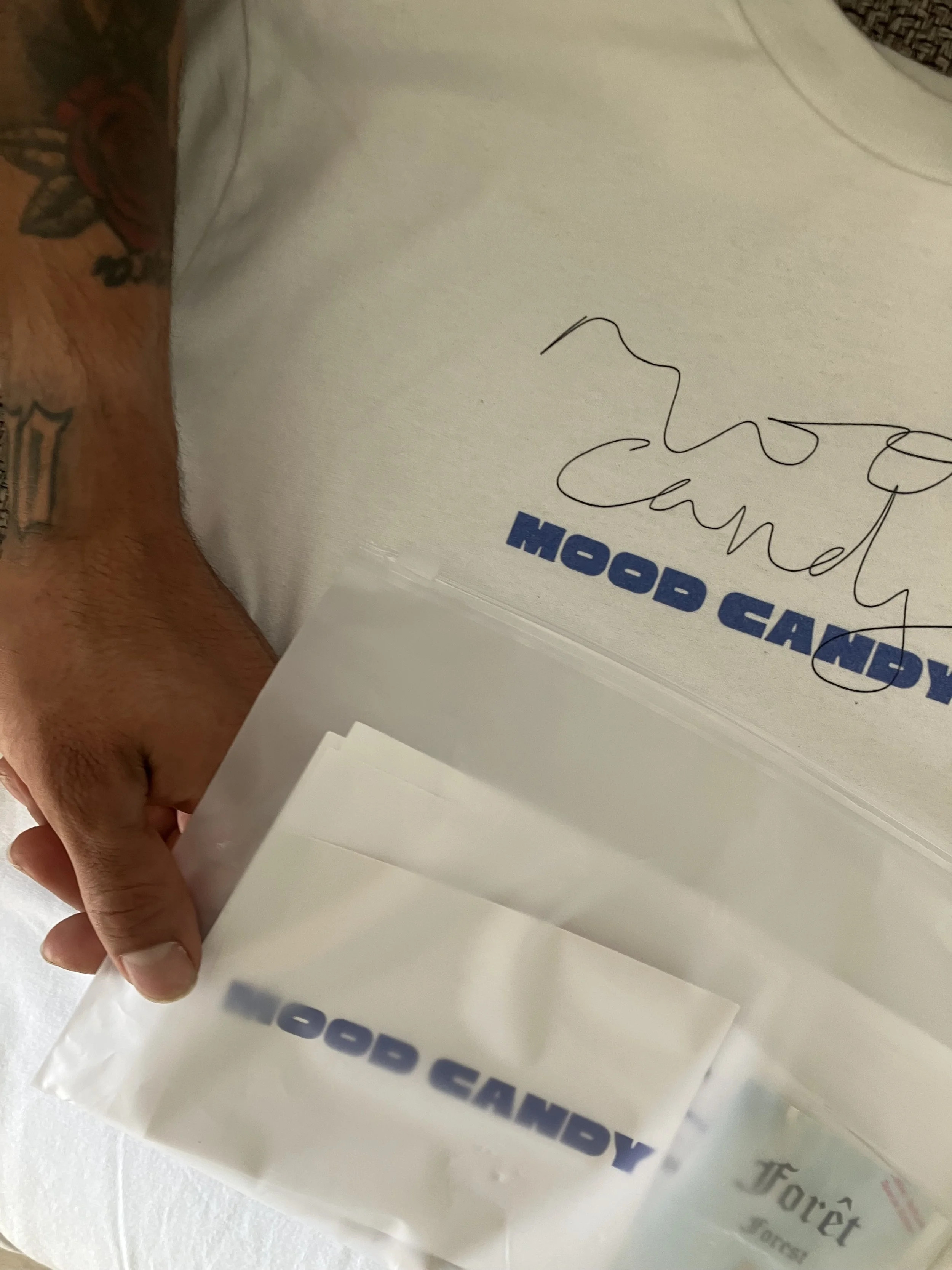 Close-up of a hand holding a plastic bag with signatures and text that is partially visible, including the words 'VOTEX' and 'CANDY'.
