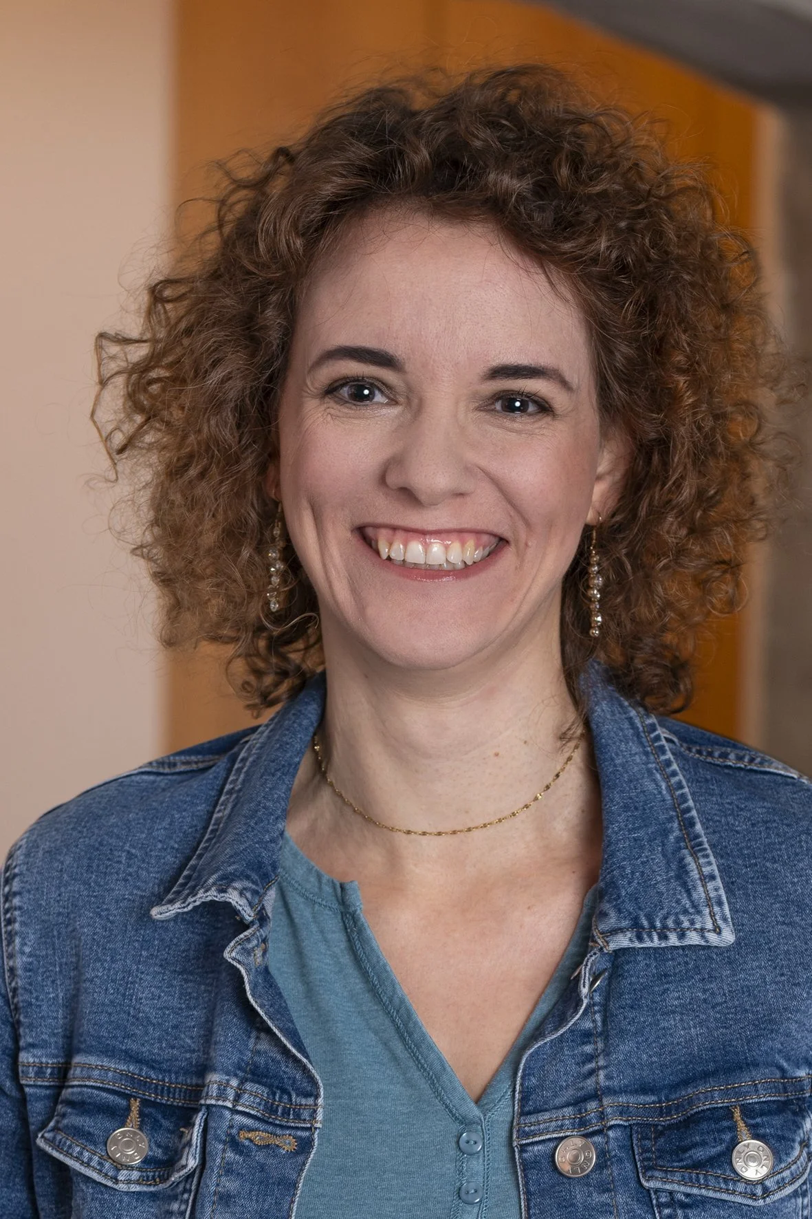 Frau mit lockigem Haar und sichtbar breitem Scheitel, die Kopfhaut ist im oberen Bereich deutlich erkennbar.