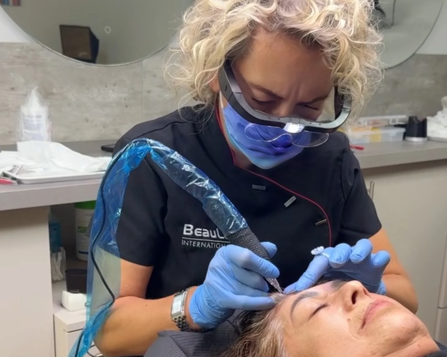 Tanja Copertino bei einer HeadSkin Coloring Behandlung, sie pigmentiert mit einem speziellen Gerät den Haaransatz einer Kundin im Salon.