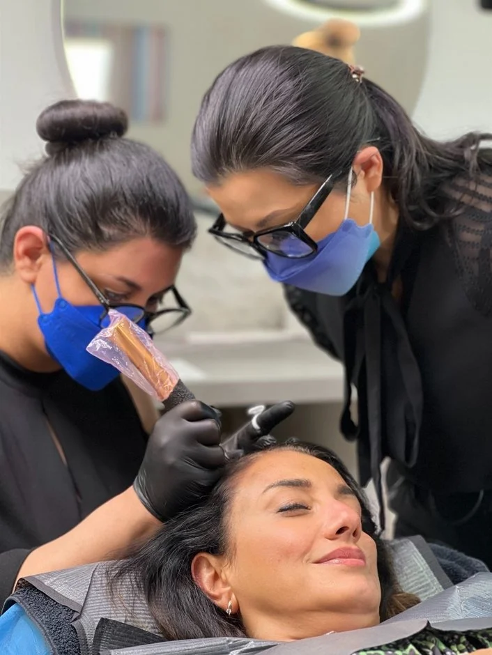 Fachkraft führt HeadSkin Coloring Kopfhautpigmentierung bei einer Kundin im Salon durch