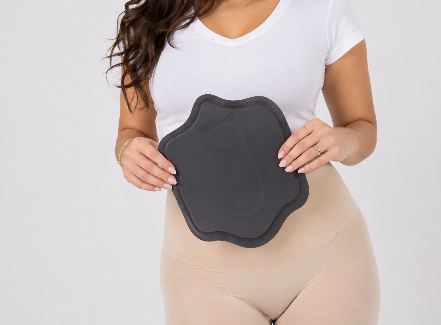 Woman holding a lipo board over abdominal compression garment after liposuction recovery
