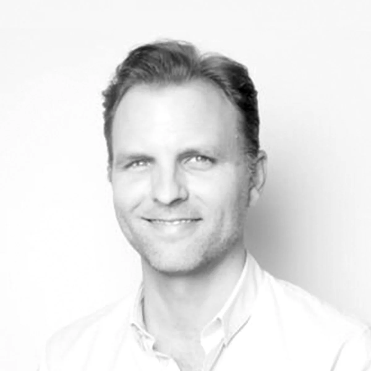 Black and white photo of a man with short dark hair, smiling and wearing a collared shirt.
