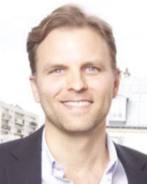 Black and white portrait of a smiling man with short, dark hair, wearing a collared shirt.