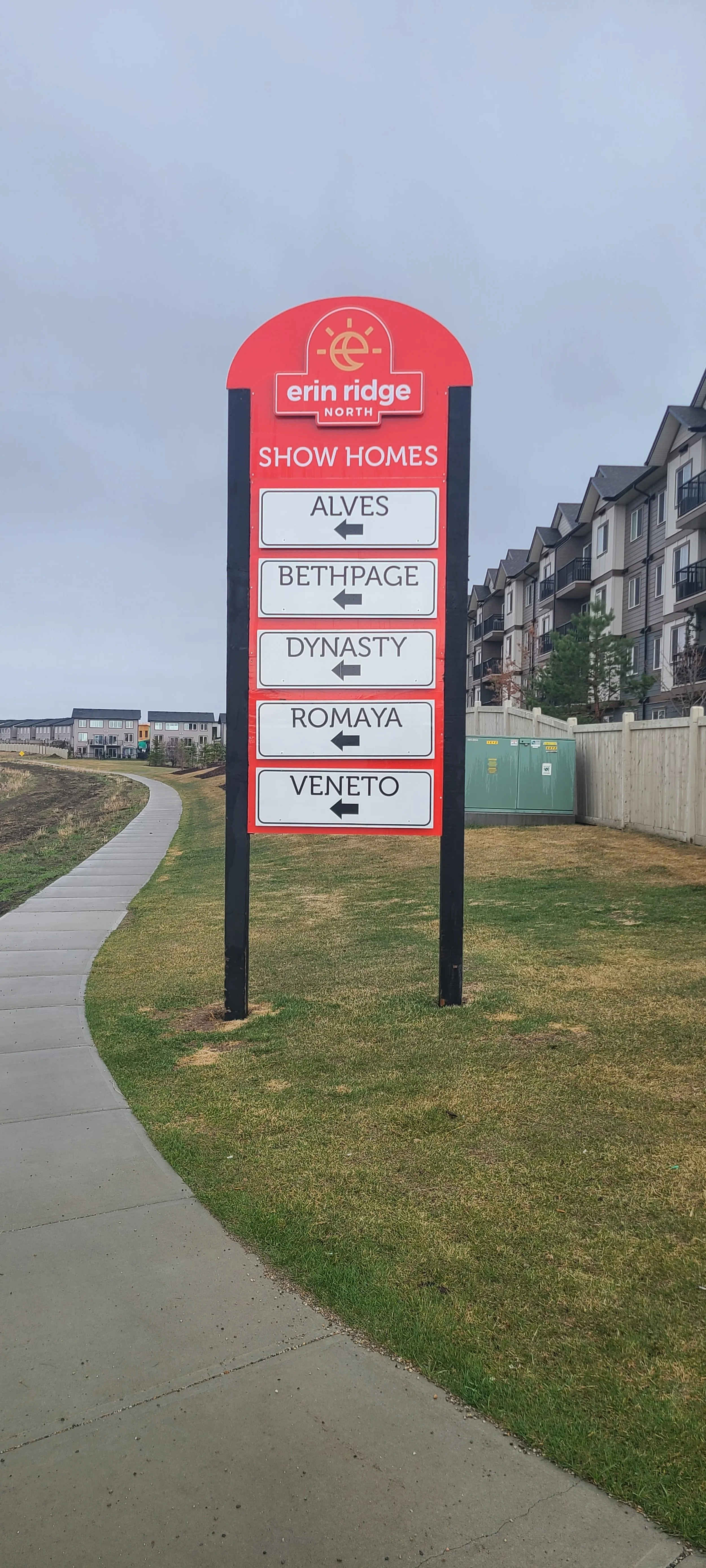 Sign for Erin Ridge North showing homes in a neighborhood, with arrows pointing left for Alves, Bethpage, Dynasty, Romaya, and Veneto