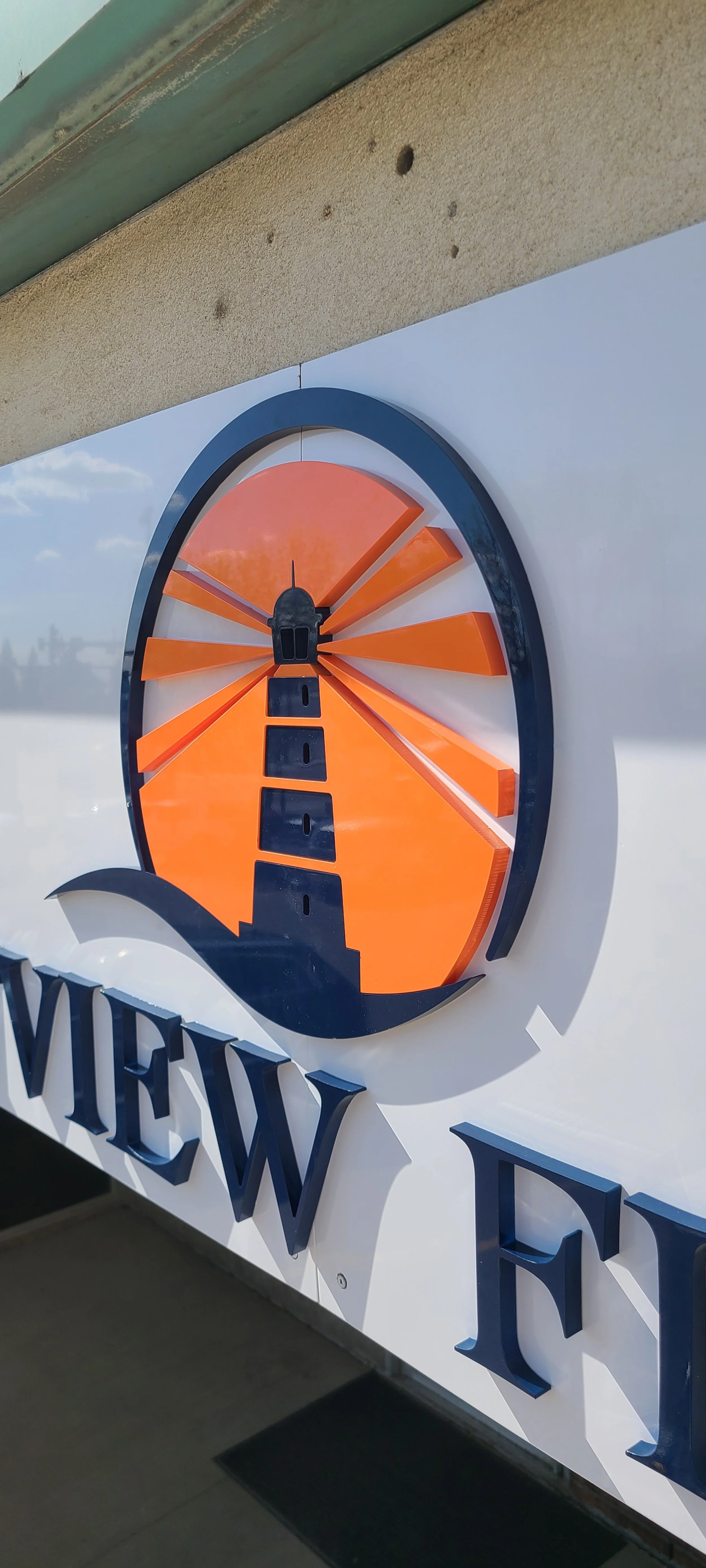 Sign with a lighthouse graphic inside a circular frame, orange rays radiating outward