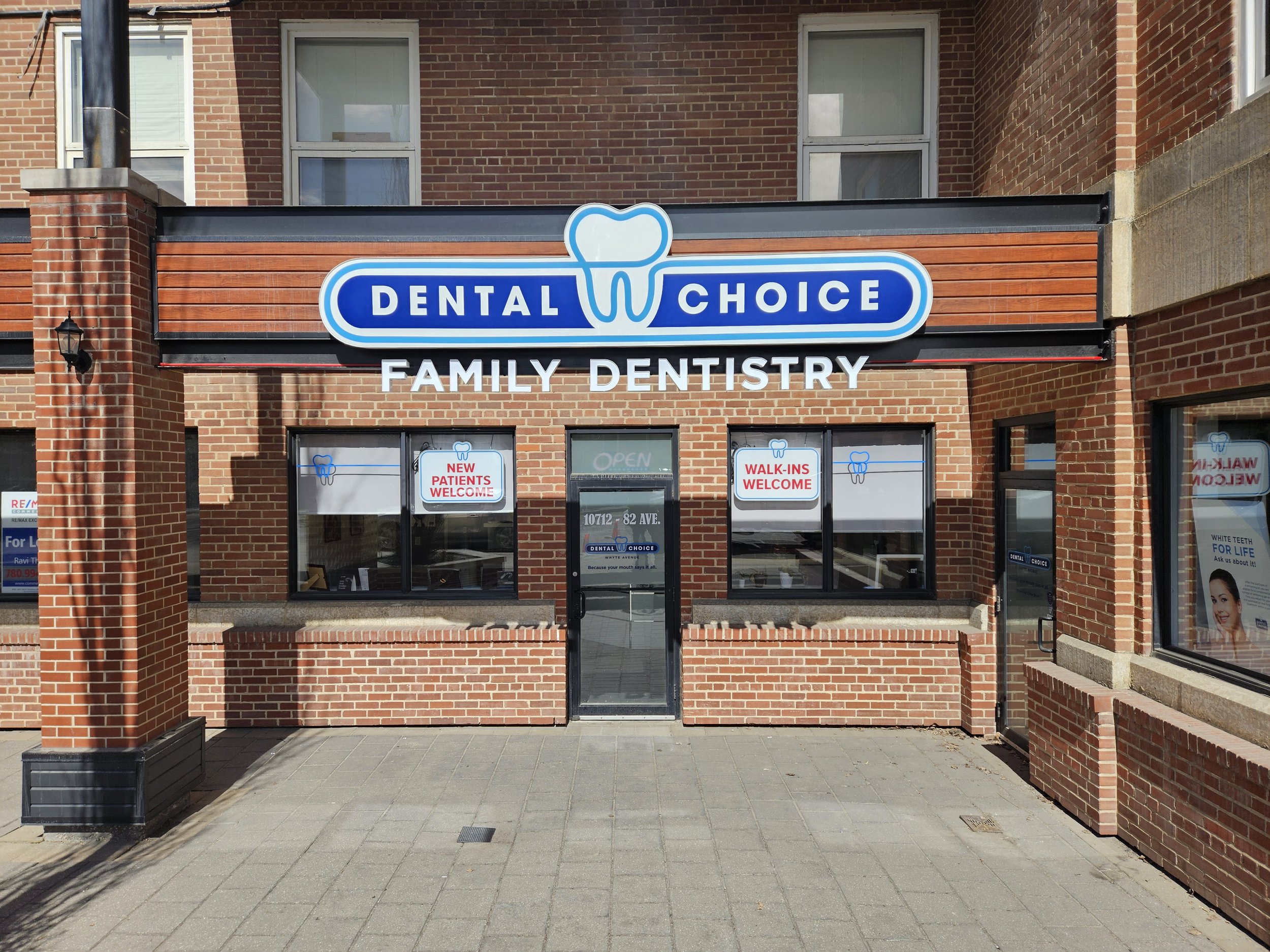 Dental Choice family dentistry clinic with brick exterior, sign featuring a tooth icon and blue lettering, and windows displaying signs for new patients and walk-ins welcome.