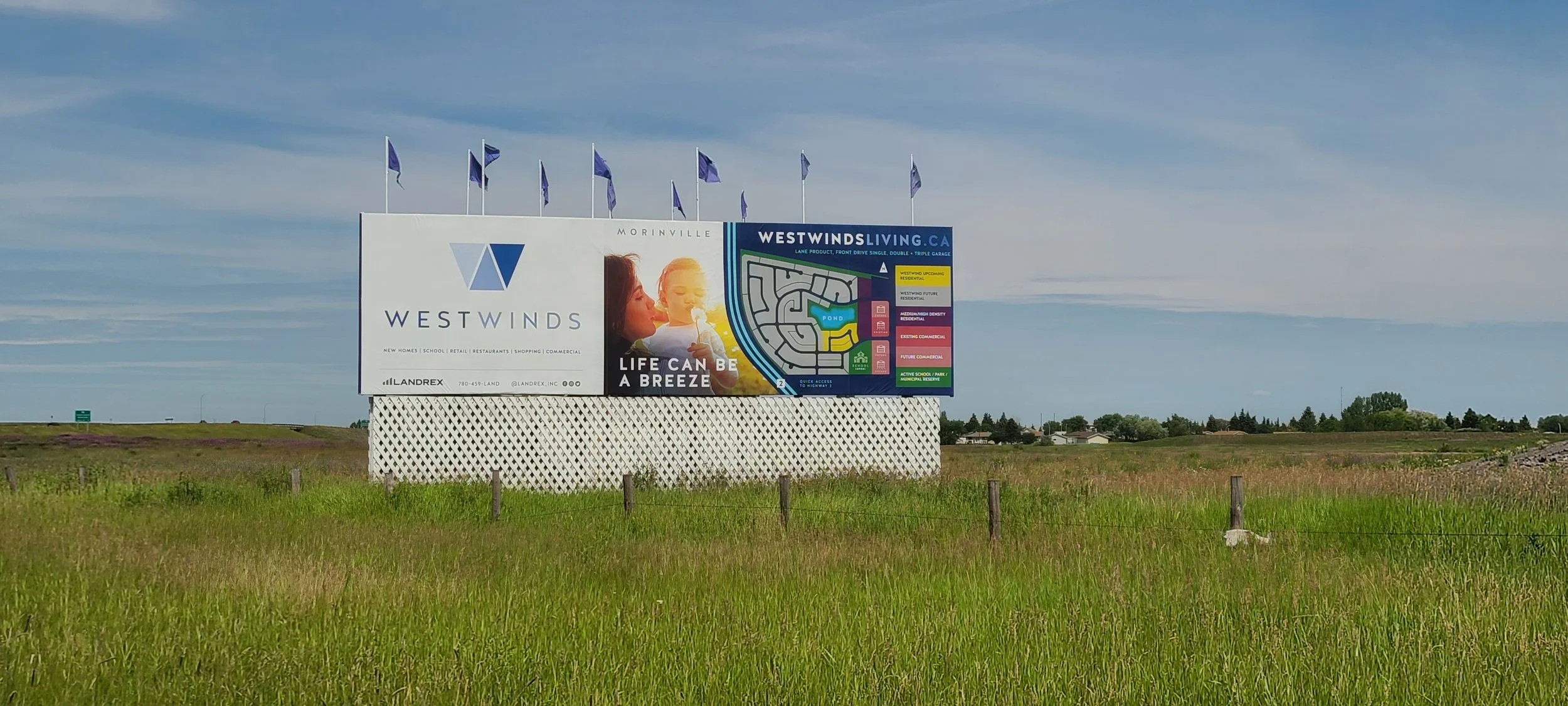 A large billboard advertising Westwinds residential community shows a woman and a child, with a scenic background and a map of the area.
