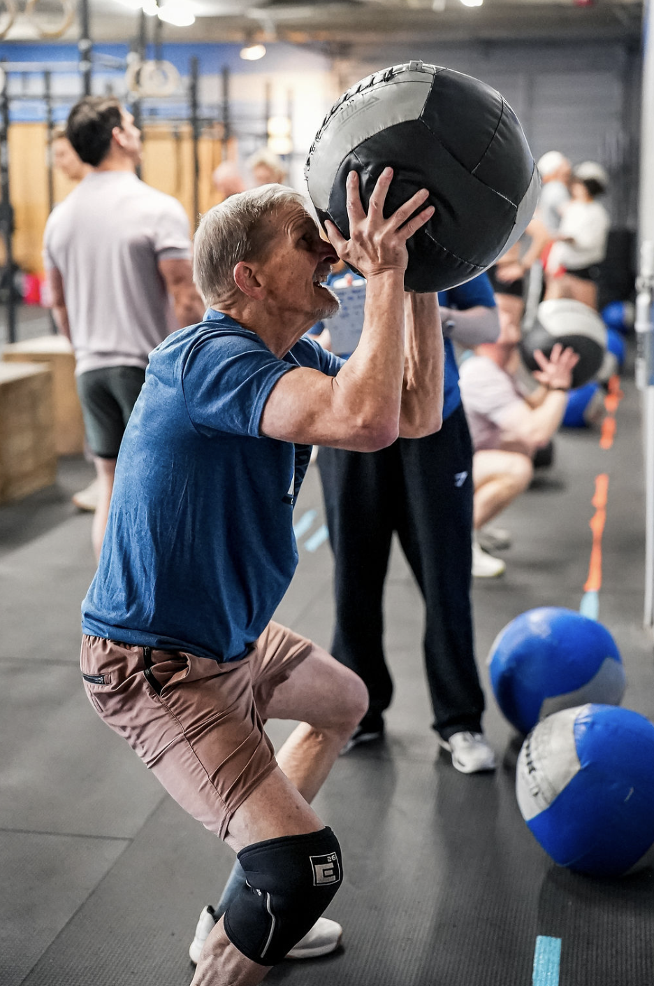 Older athlete performing a wall ball shot during a CrossFit class at CrossFit Wash Park in Denver.