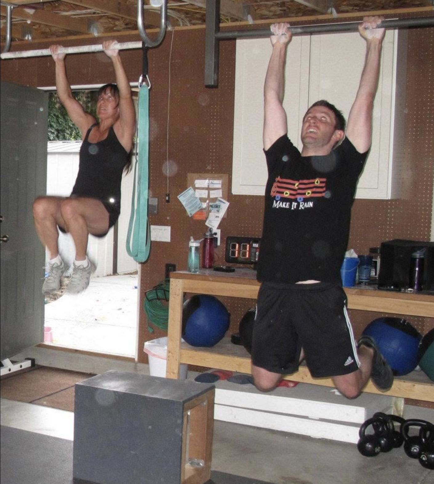 Two athletes doing pull-ups in CrossFit Wash Park’s original garage gym.