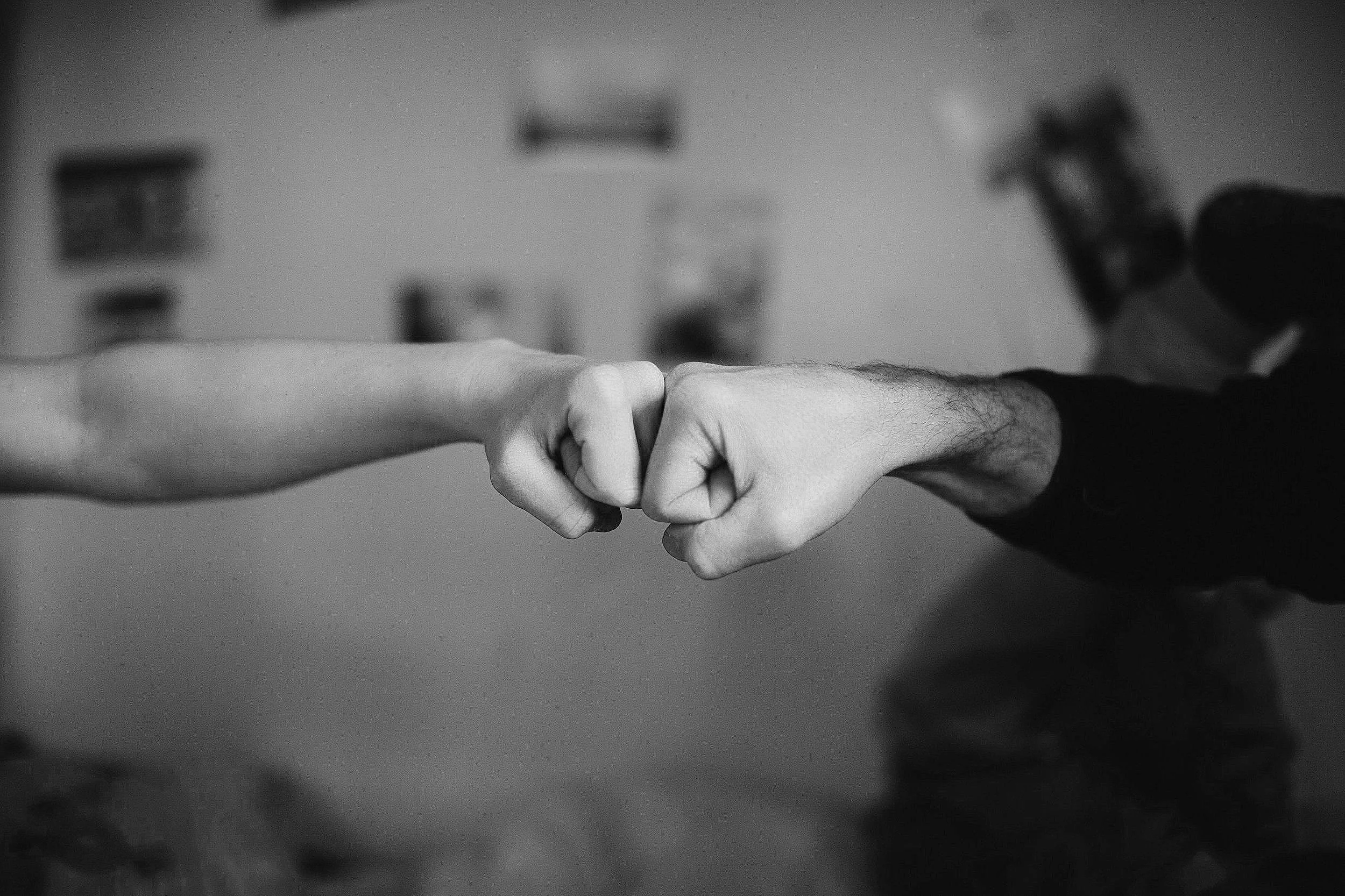 Schwarz-weiß-Foto von zwei Händen, die sich in einem Bump-Berührung berühren.