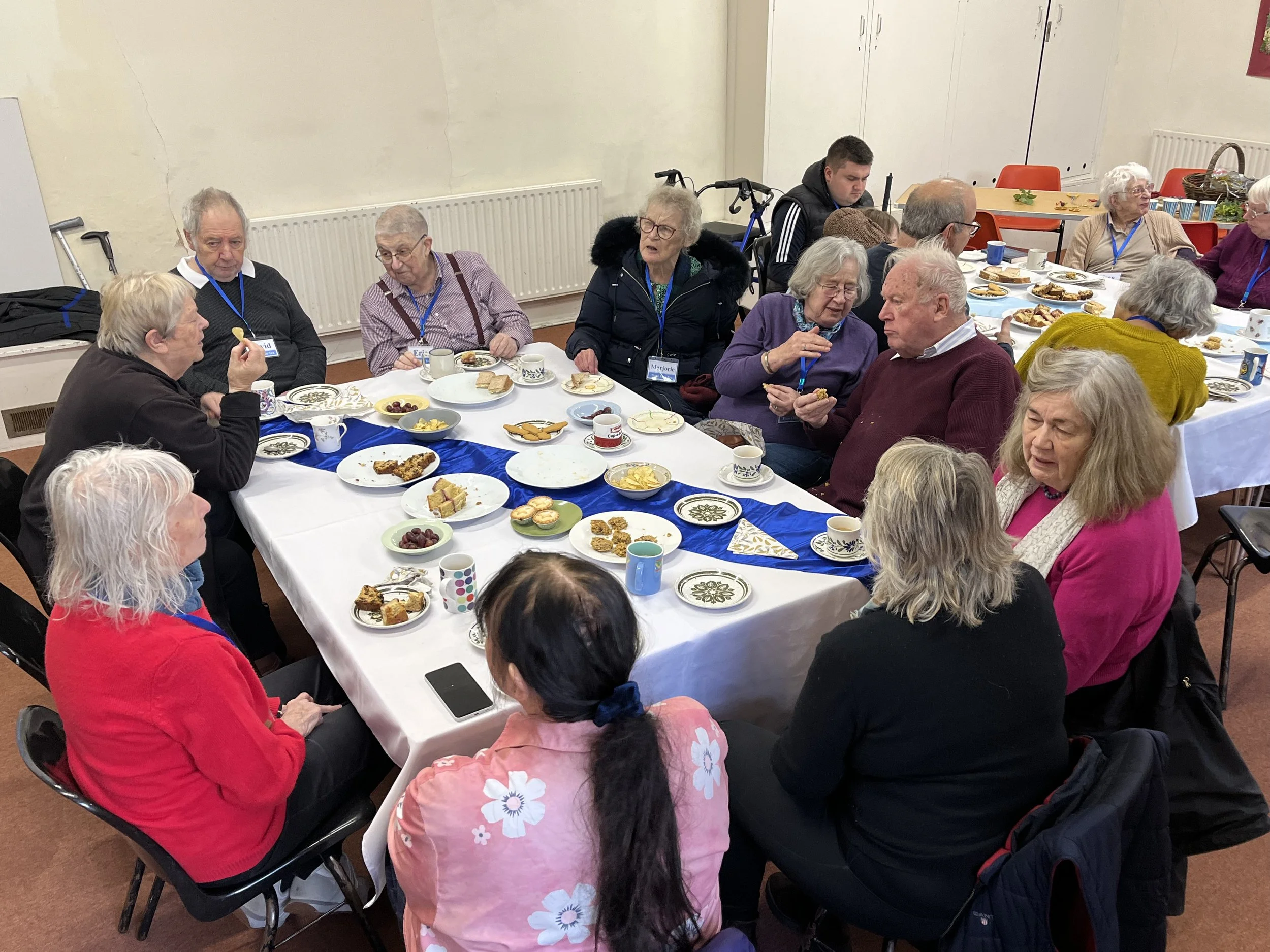A group of elderly people sitting around a table enjoying a meal and conversation at a social gathering.