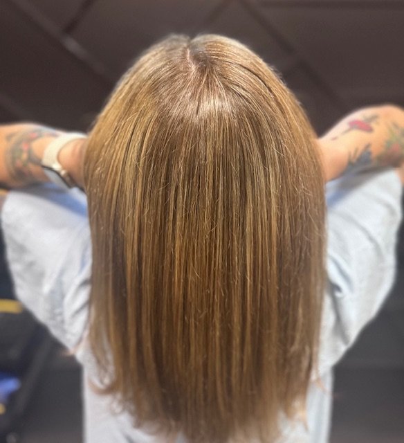 Top view of a person's straight, shoulder-length hair with a warm blonde color.