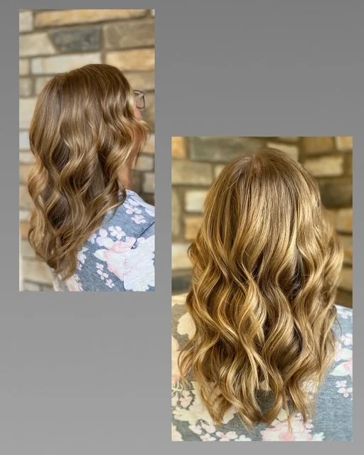 Side and back view of a woman with long, wavy, blonde hair, standing in front of a stone wall.
