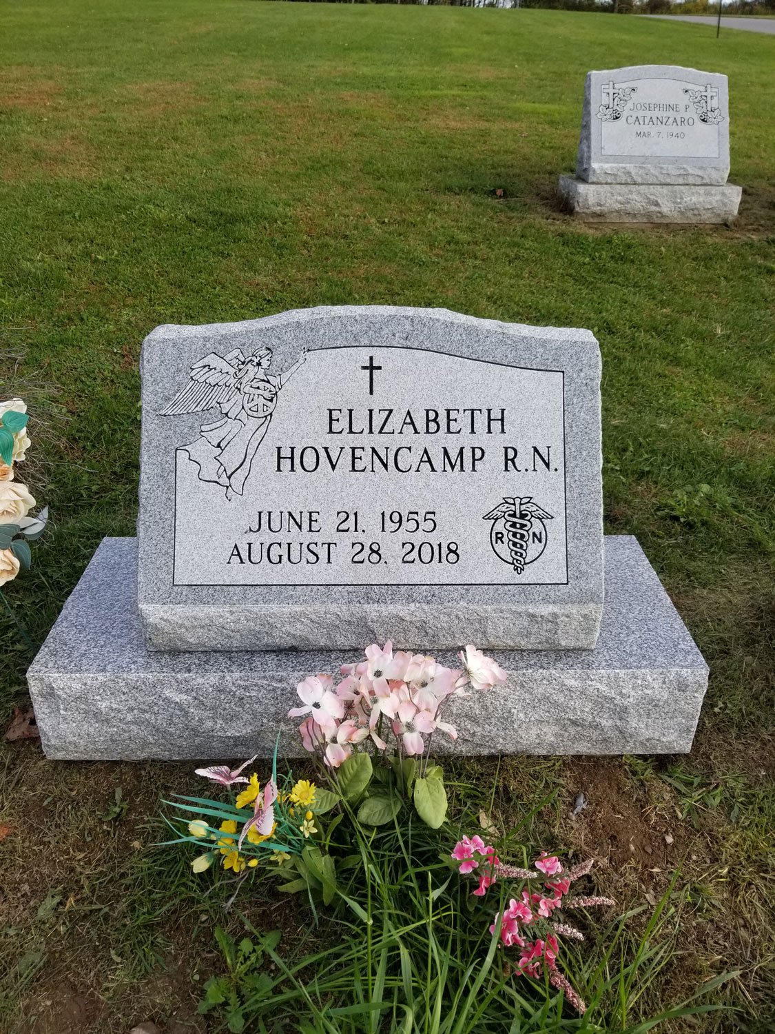 Grave of Elizabeth Hovencamp R.N., with flowers in front, in a cemetery with another grave in the background.