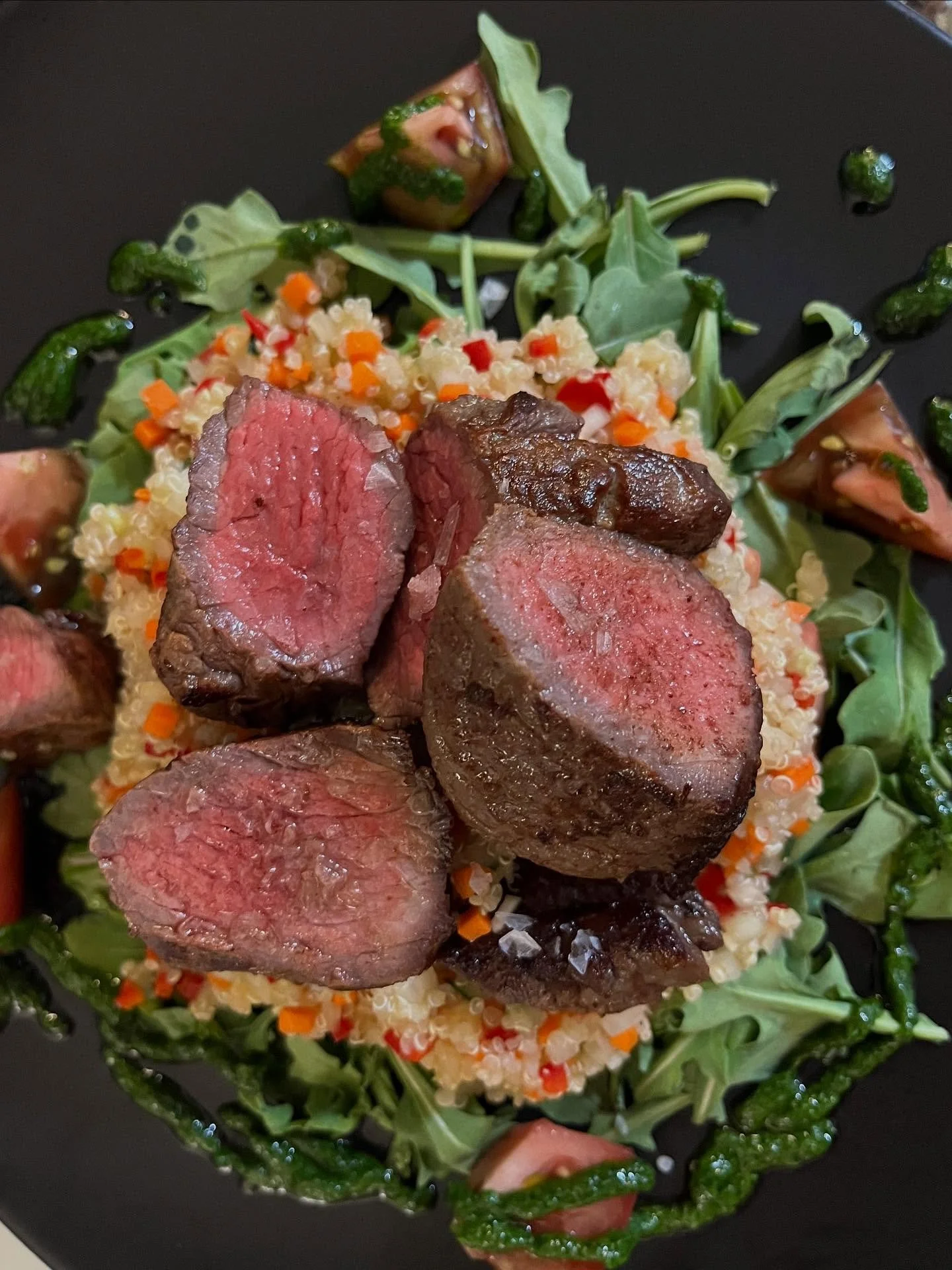 Grilled sirloin over a spicy quinoa salad, a bed of rocket, and farm fresh heirloom tomatoes with a herb sauce 🍅