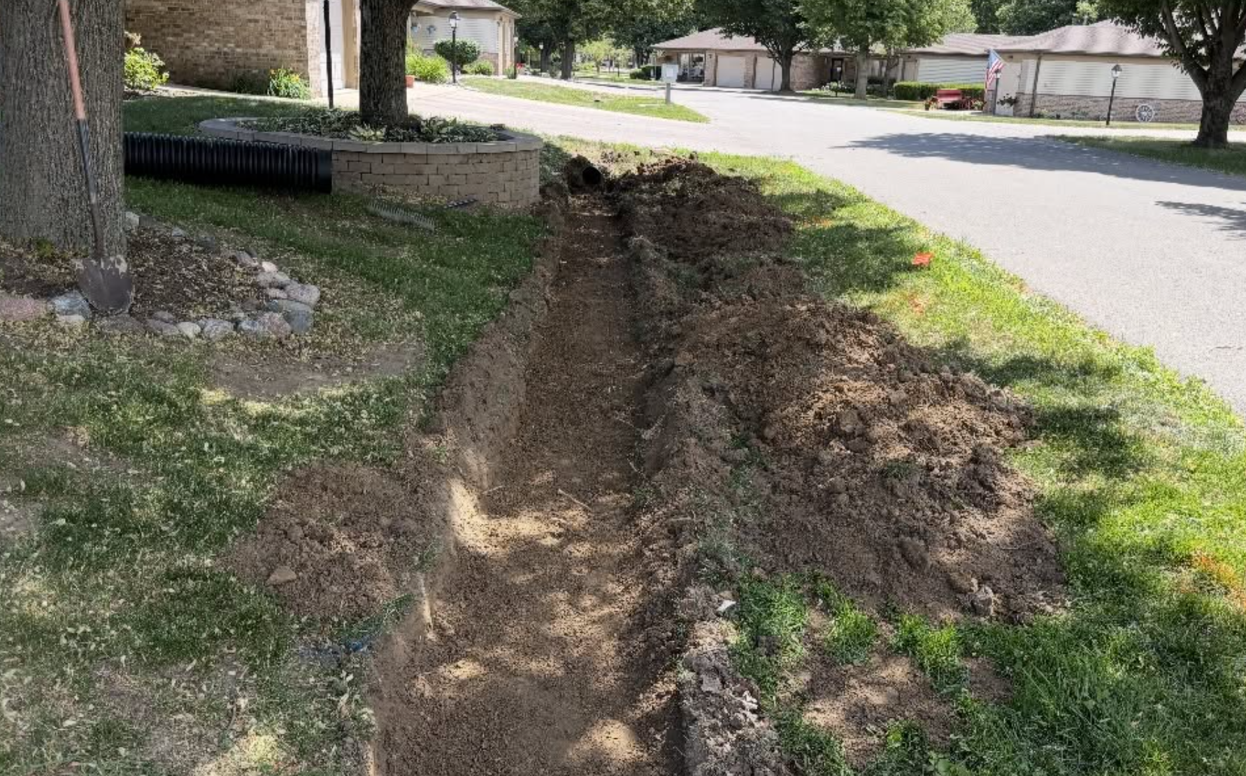 Excavated trench for underground drainage pipe installation completed by OPS Outdoor Property Services.