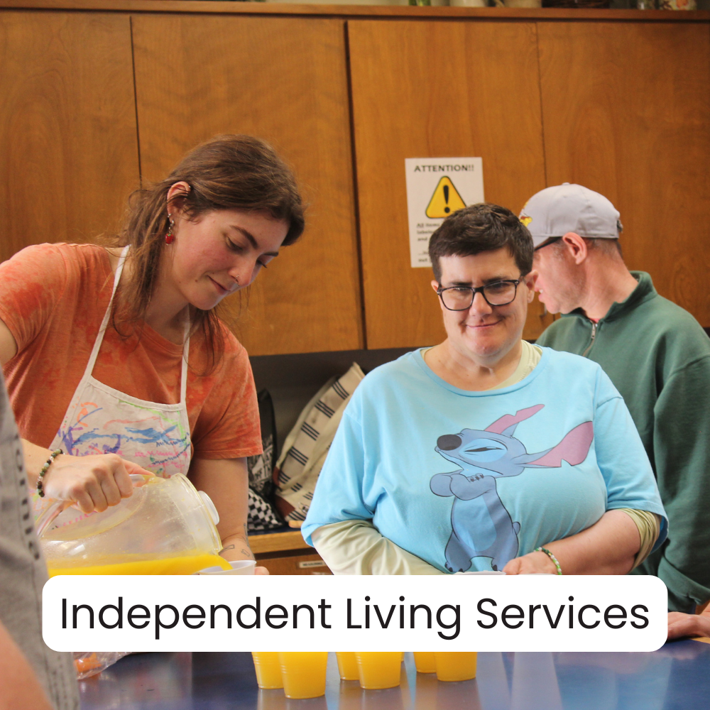 People serving orange juice at a table during an indoor event affiliated with Independent Living Services.