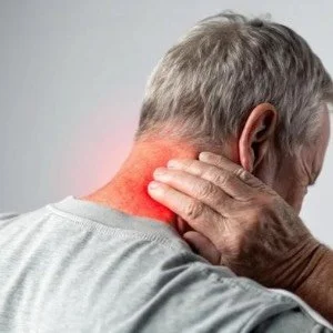 Older man holding his neck in pain with visible redness indicating discomfort or inflammation.