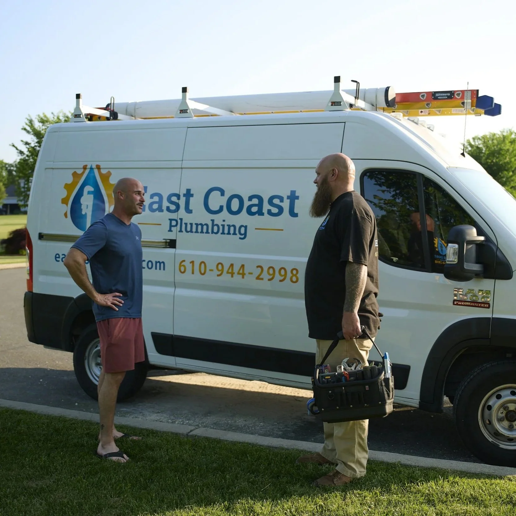Commercial plumbers discussing building plumbing replacement needs beside service vehicle, highlighting proactive maintenance and infrastructure upgrade planning.