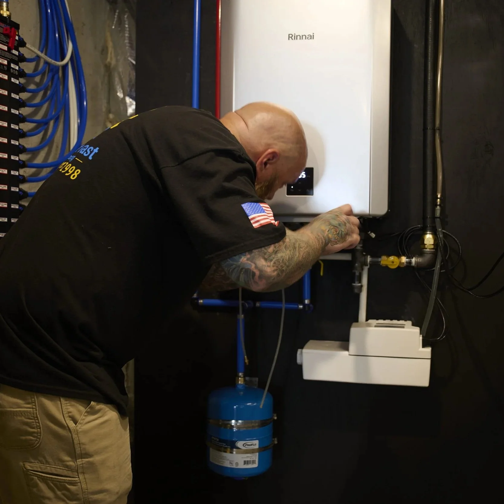 Plumber servicing a tankless water heater, diagnosing performance issues that can cause cold water interruptions during showers.