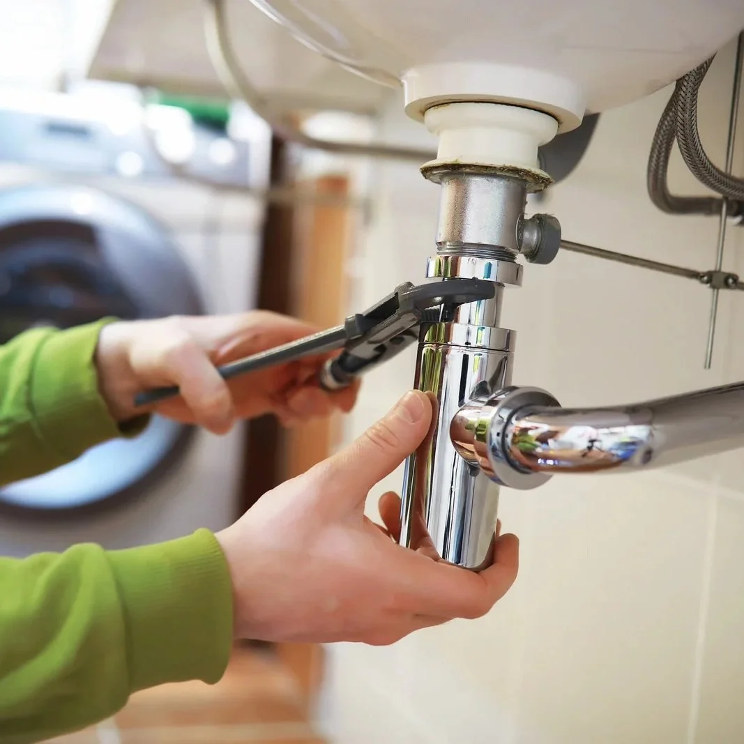 Plumber performing sink drain maintenance during routine plumbing inspection covered under annual rental property maintenance contracts.
