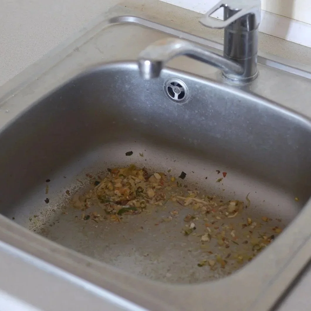 Kitchen sink containing food scraps that can cause drain clogs and recurring plumbing issues in rental properties.