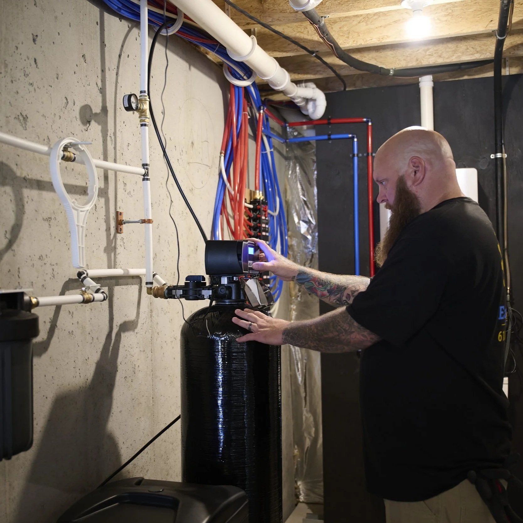 Plumber inspecting commercial water heater system, comparing tankless and storage tank performance for restaurant hot water demand.
