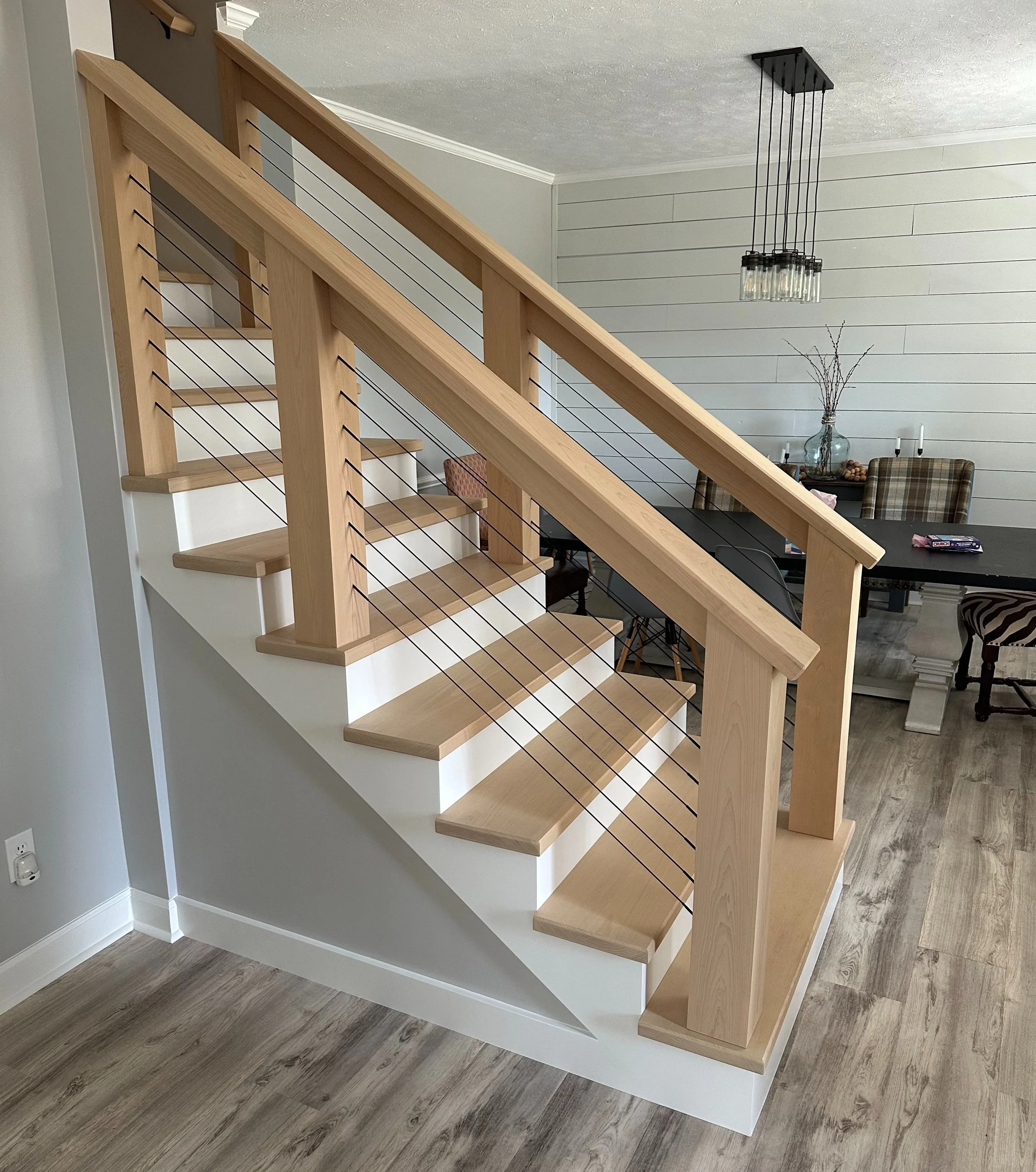 Wood staircase with cable railings leading to an upper floor in a modern home interior.