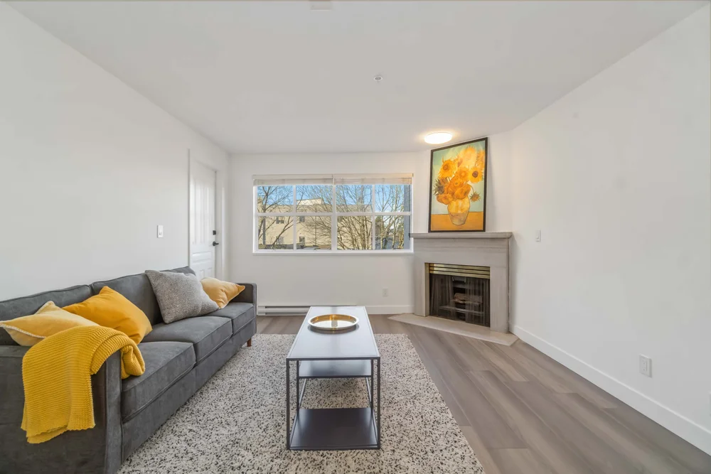 Staged living room with grey sofa, yellow throw and gas fireplace