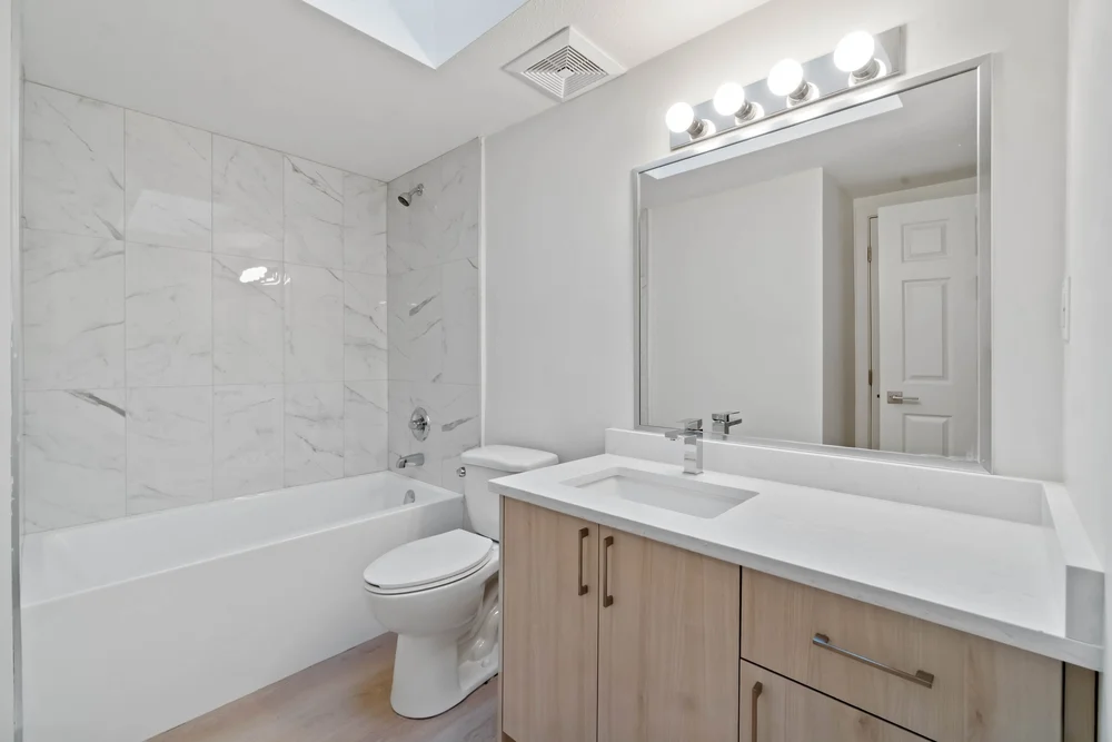 Bathroom with skylight and marble look tub surround