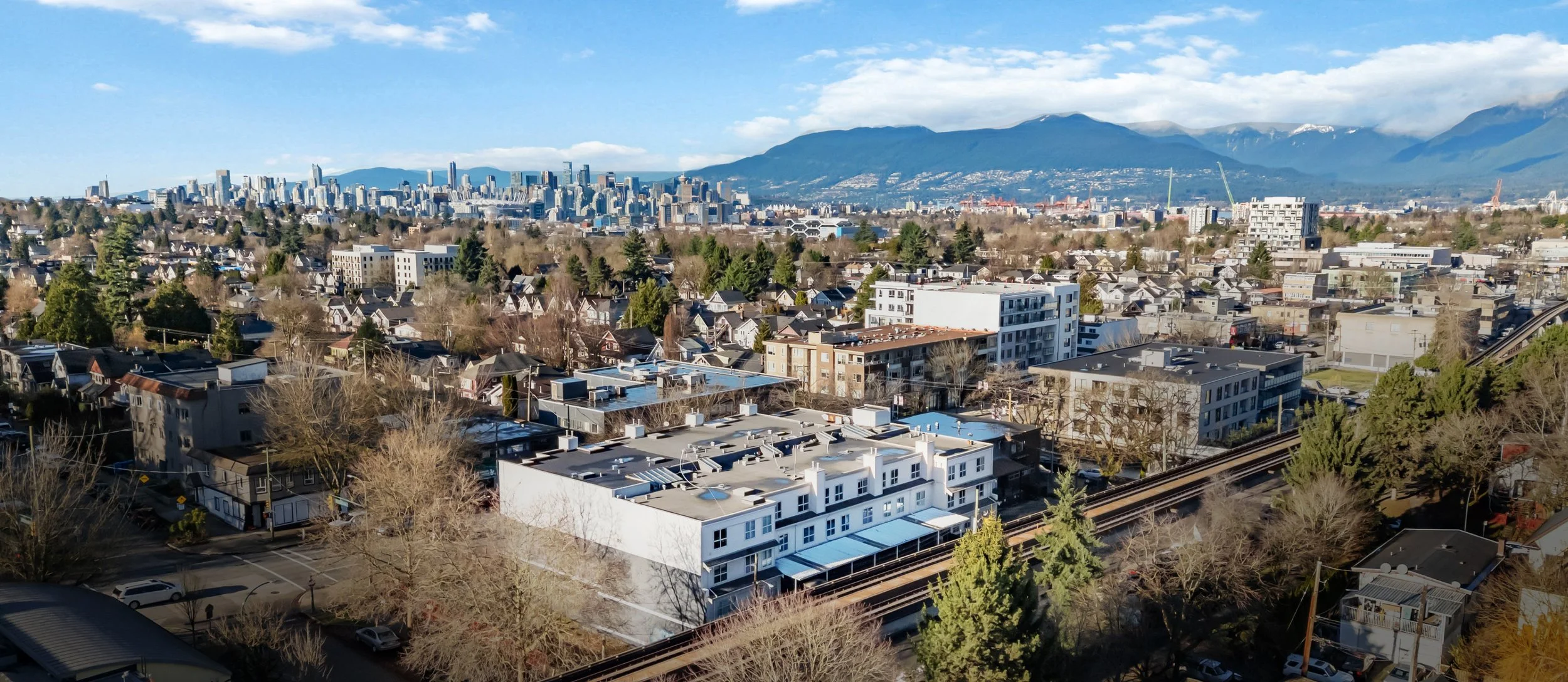 Aerial drone view over the neighbourhood with mountains on the horizon and the building mid frame